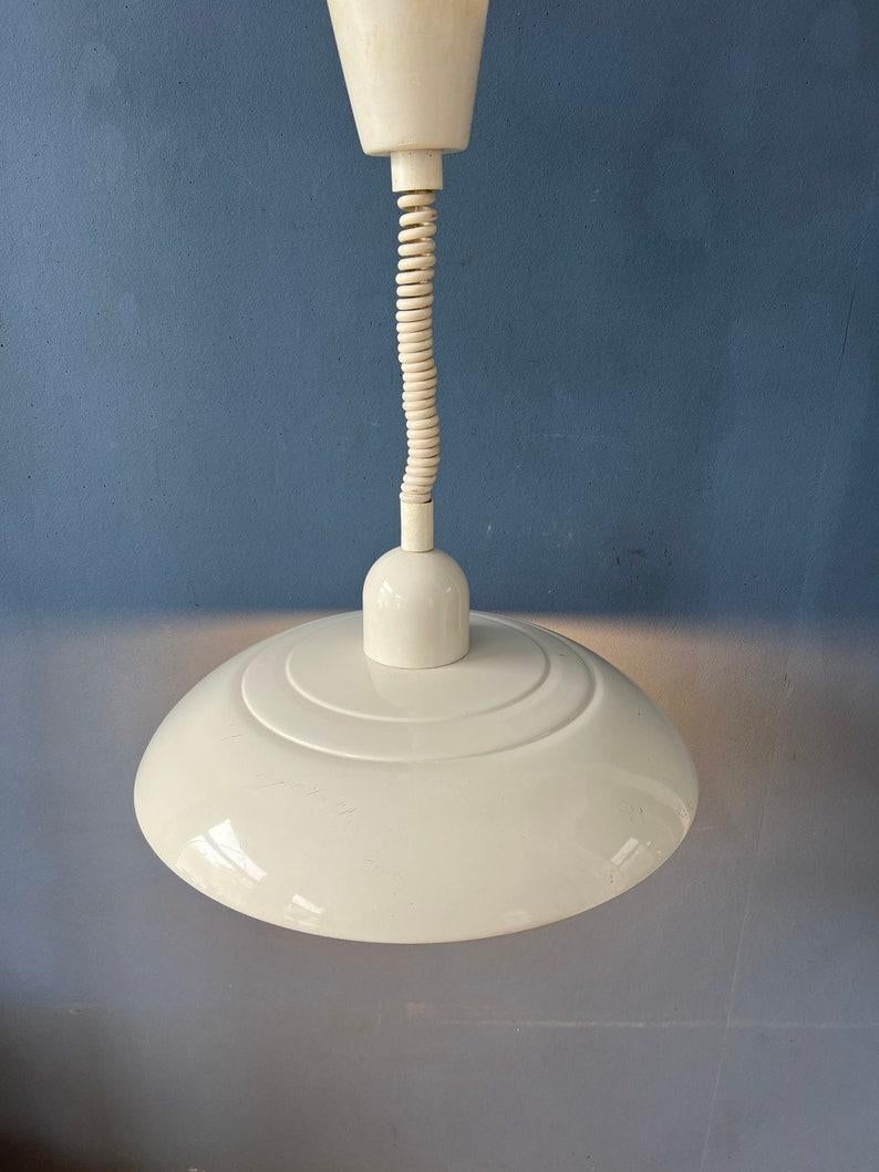 Beautiful beige vintage space age pendant lamp. The lamp has shiny beige lacquer. It can easily pulled up and down with the rise-and-fall mechanism. The lamp is made out of metal and has a plastic top and ceiling cap. The lamp requires one E27/26