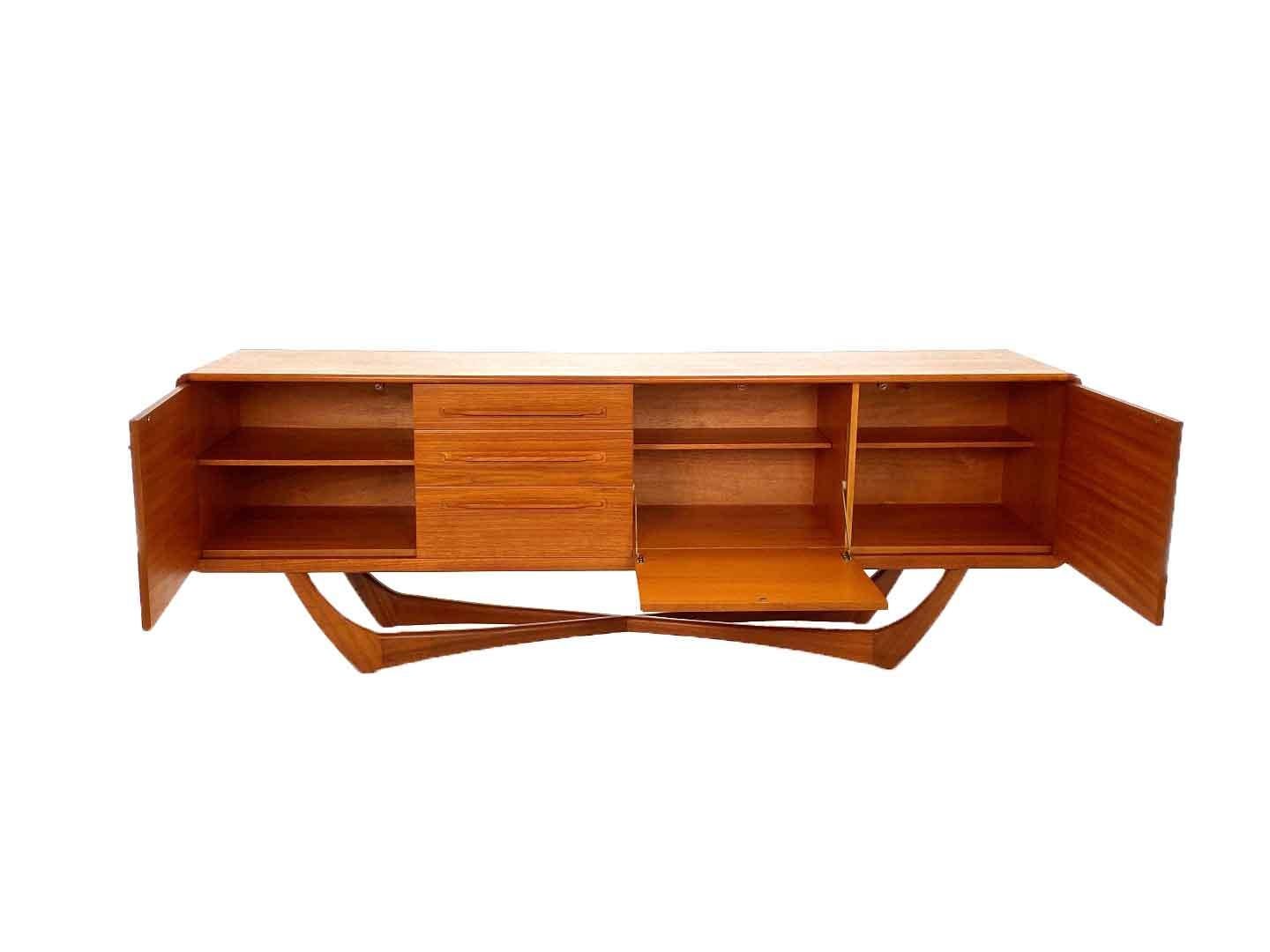 Rare vintage Beithcraft sideboard by Val Rossi produced in Scotland in the 60's. The sideboard has two doors, a cover and three drawers. The sideboard is very unique through its consistent crossed legs, also called spiderlegs. Through the very