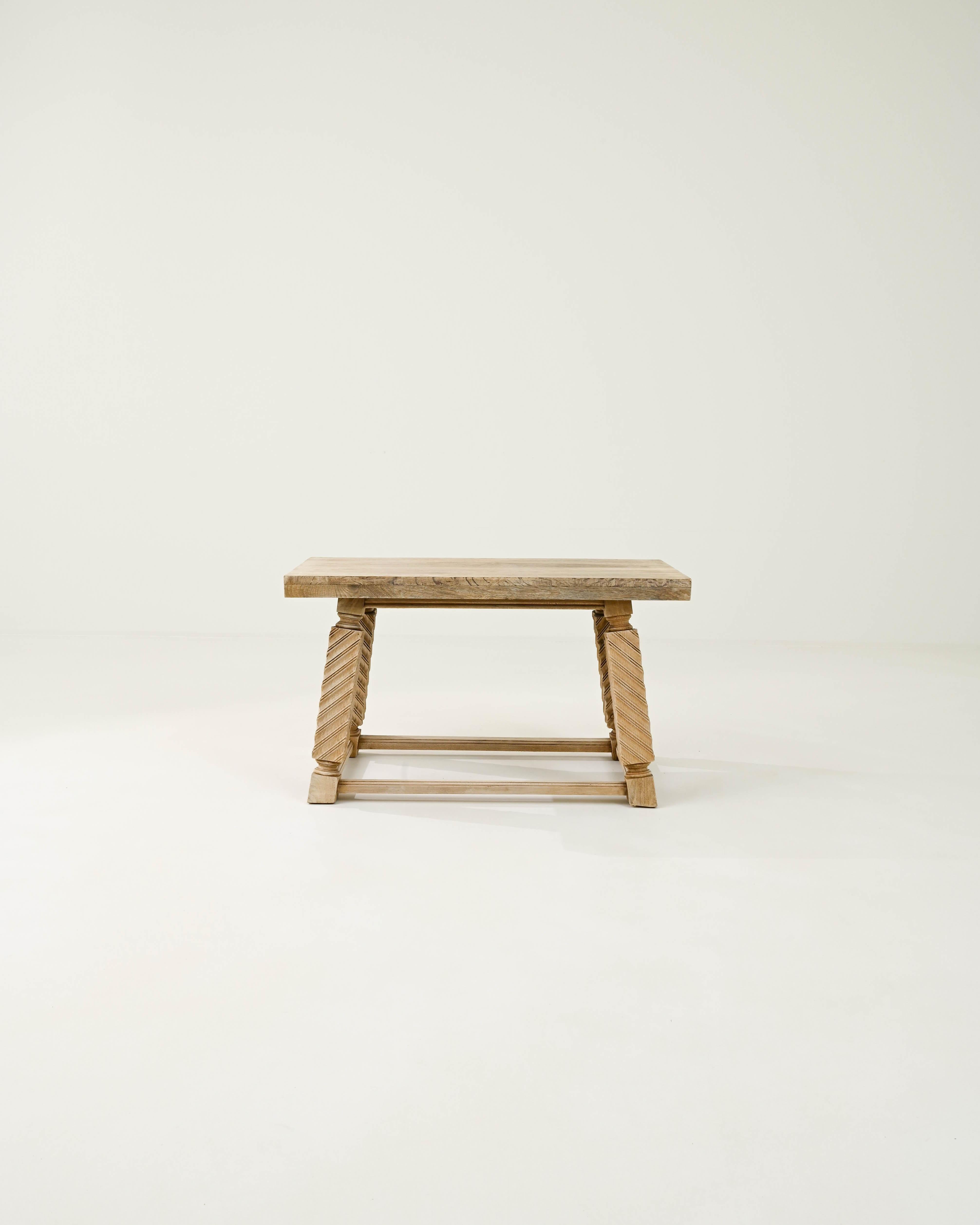 A coffee table made from oak and beech wood, from 20th century Belgium. This stylish table is composed with a classical sensibility, resting on unique square legs, their blocky form given a visual twist by carved ogees. The simplicity of the table