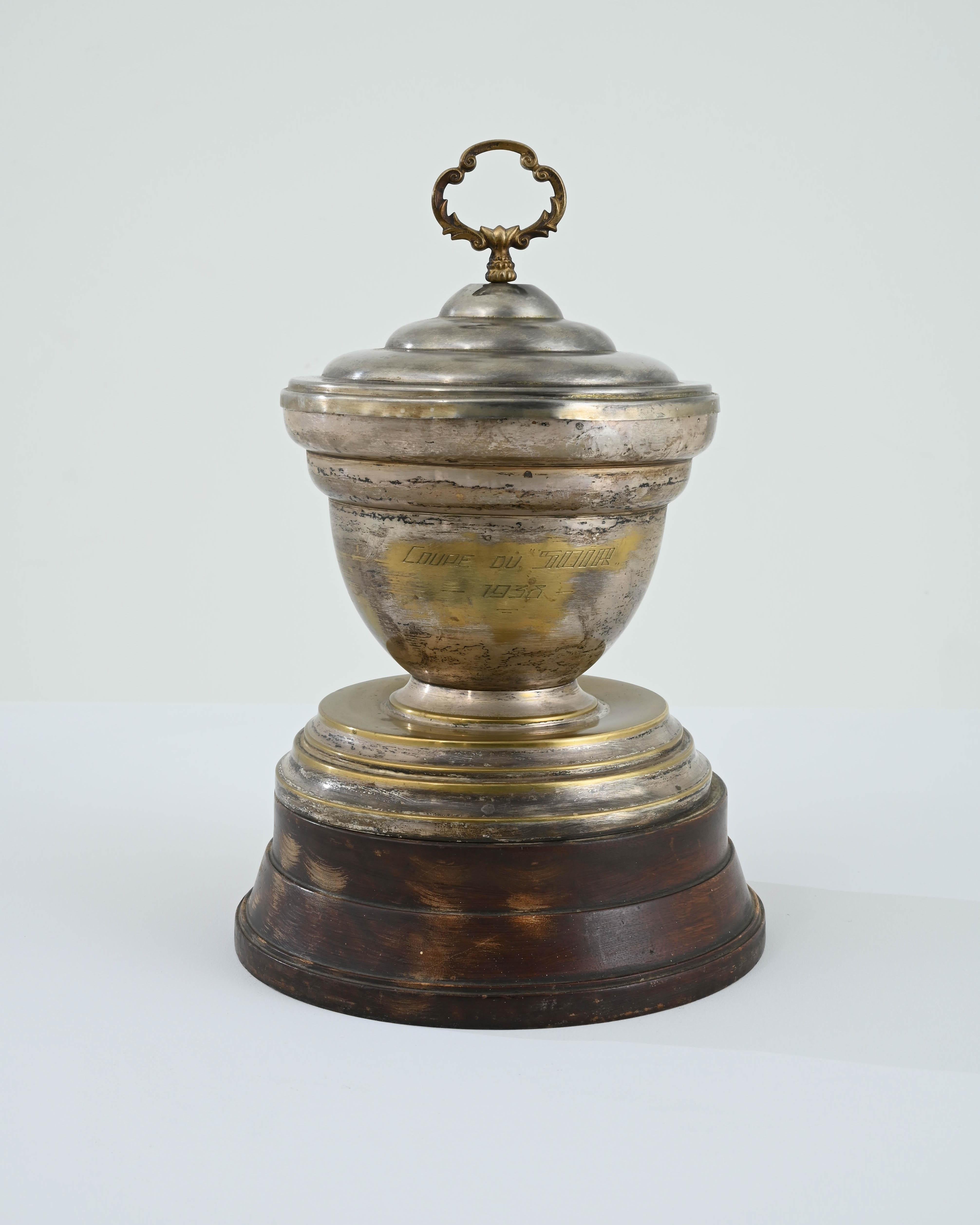 A brass trophy cup from Belgium, circa 1938, standing on a polished wooden base. Emblazoned with the name of the contest, “Coupe du SOIR,” gentle weathering gives a sense of nostalgia to this evocative accent-- passing through the hands of