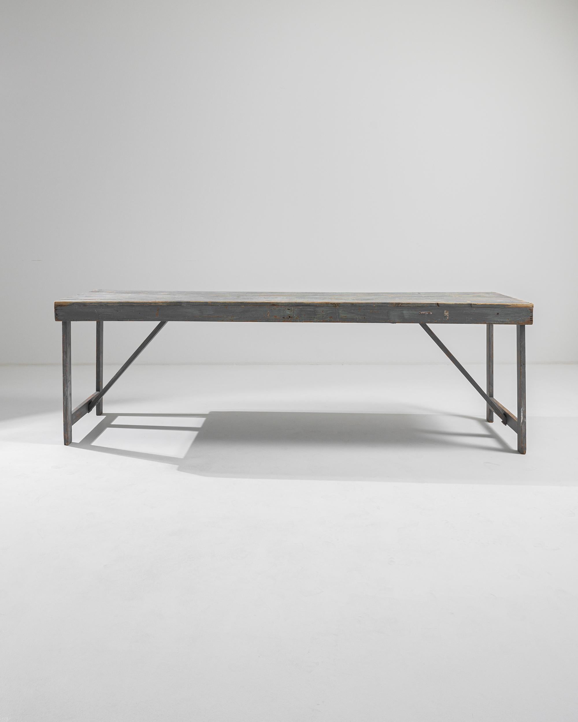 Straightforward and sincere, this vintage wooden table has a rustic pragmatism. Made in Belgium in the 20th century, a tabletop of wooden boards sits atop a simple frame; slanting struts provide an angular counterpoint to the rectilinear form. The