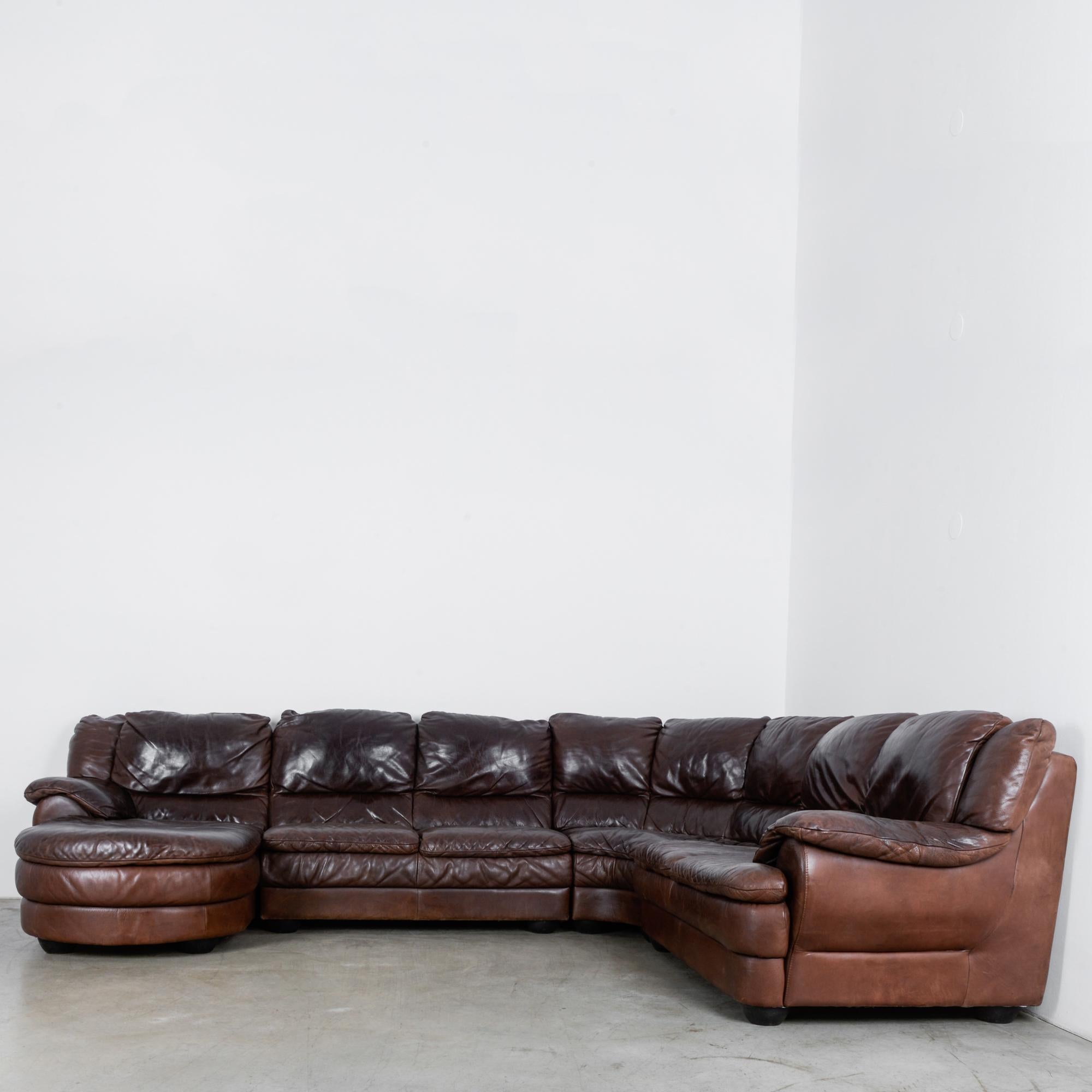 This leather sofa was made in Belgium, circa 1980. The four-piece sectional set can be arranged into a U-shape and includes a chaise at one end. The sofa is set low, and the roomy seats and cushioned armrests offer relaxation and style. The glossy,