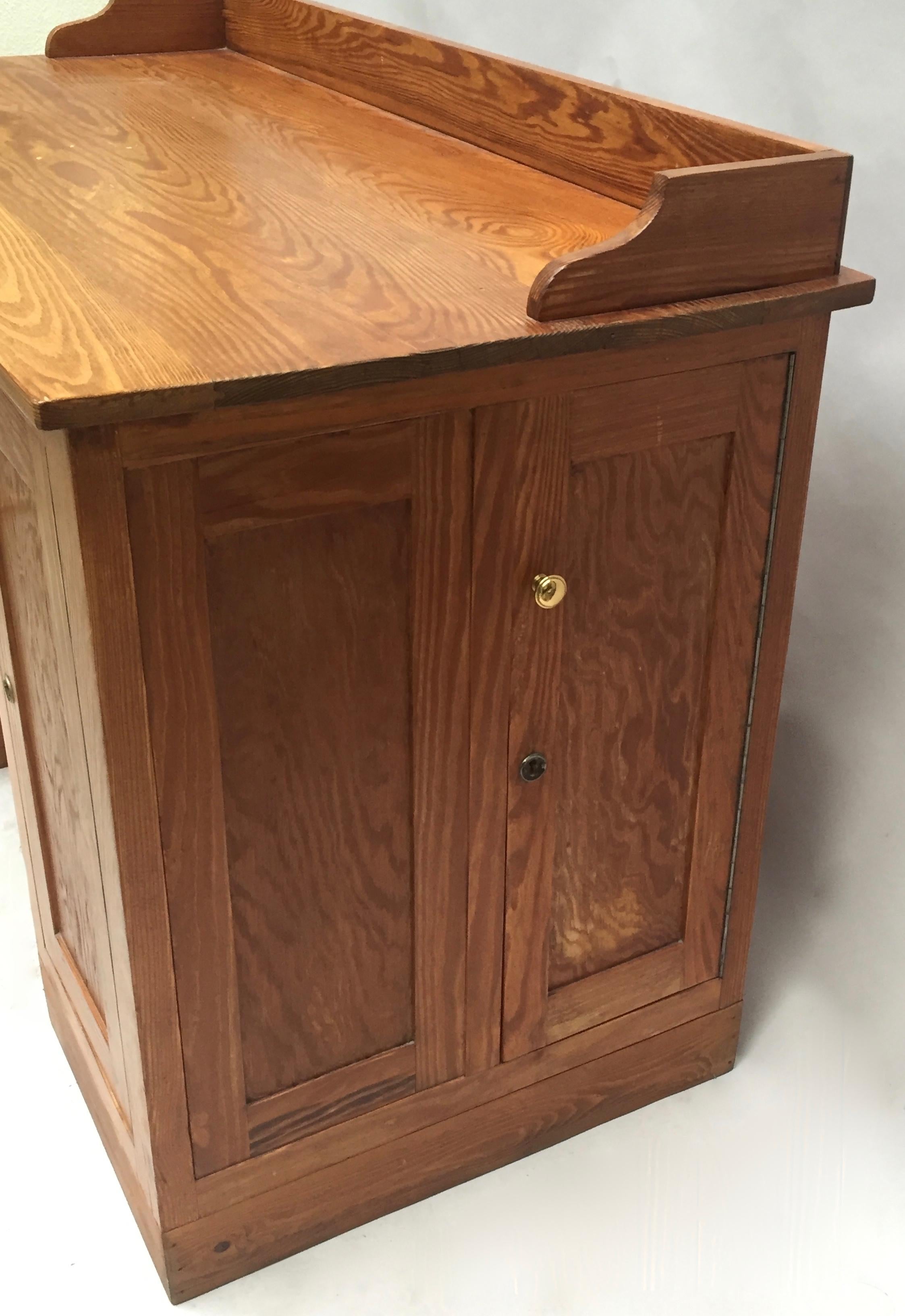 Classical Belgian School Masters desk made from solid heart pine wood boards by Dox of Lier, Belgium, circa 1940. There are 4 doors each opening to reveal an interior with one shelf  (one on each side, one right and one left of the kneehole) .