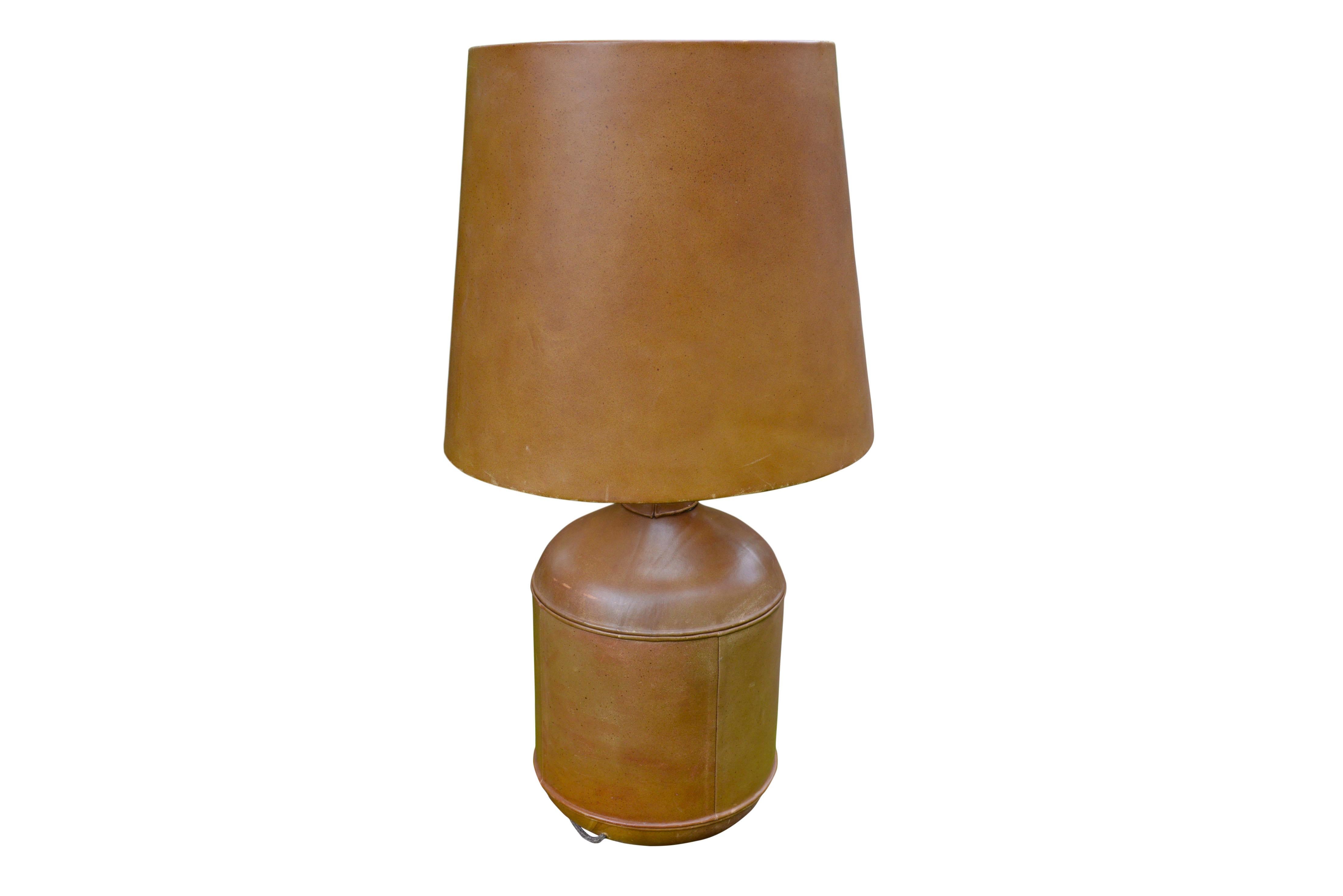 An impressive leather covered table lamp of generous proportions. The lamp base and the lamp shade are recovered with stitched saddle color leather. Beautiful patina.