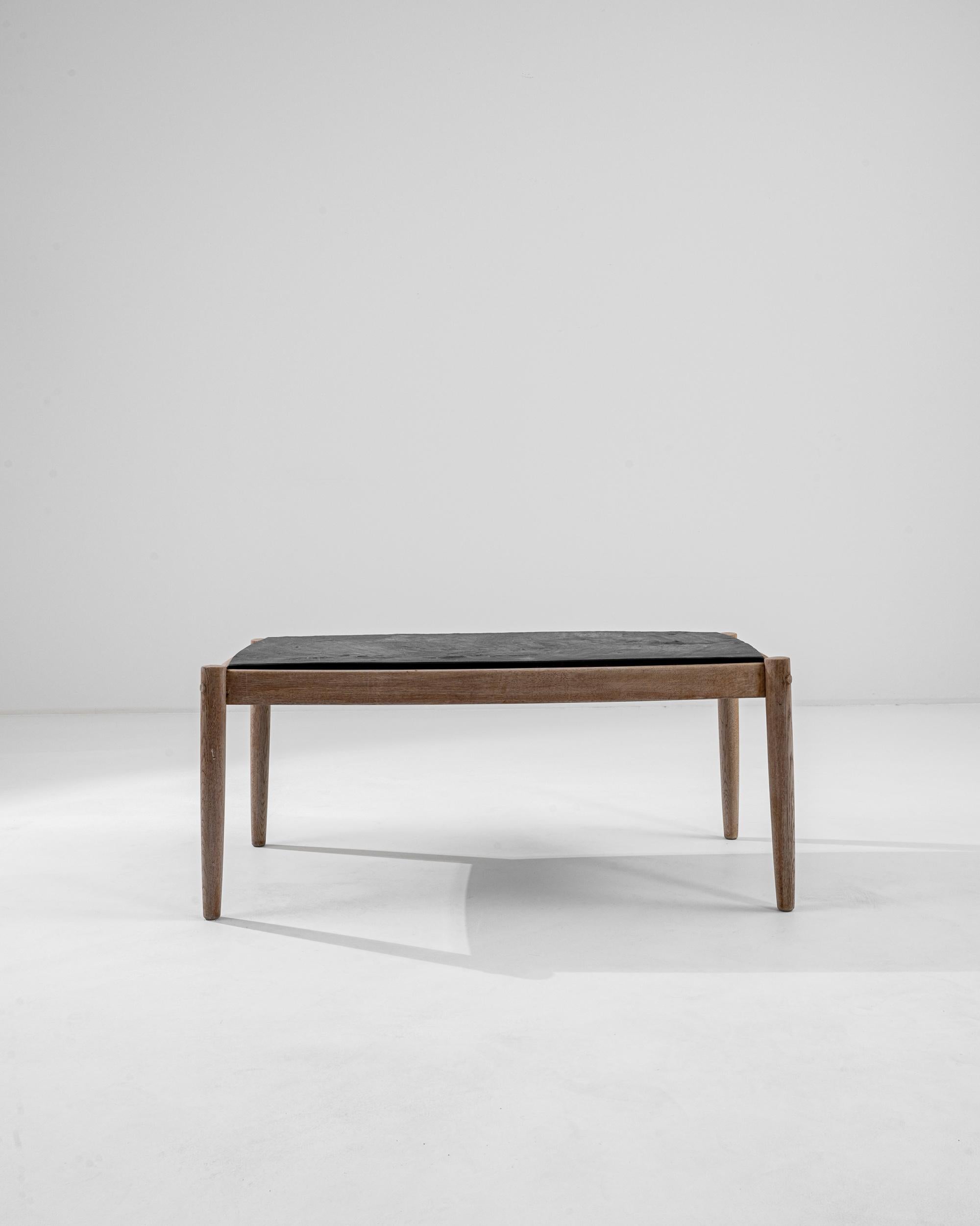 A wooden coffee table with a stone top made in 20th century Belgium. A simple construction composed of four legs, aprons, and a stone top paints an image of contemplative elemental simplicity. The stone top that rests upon freshly bleached oak