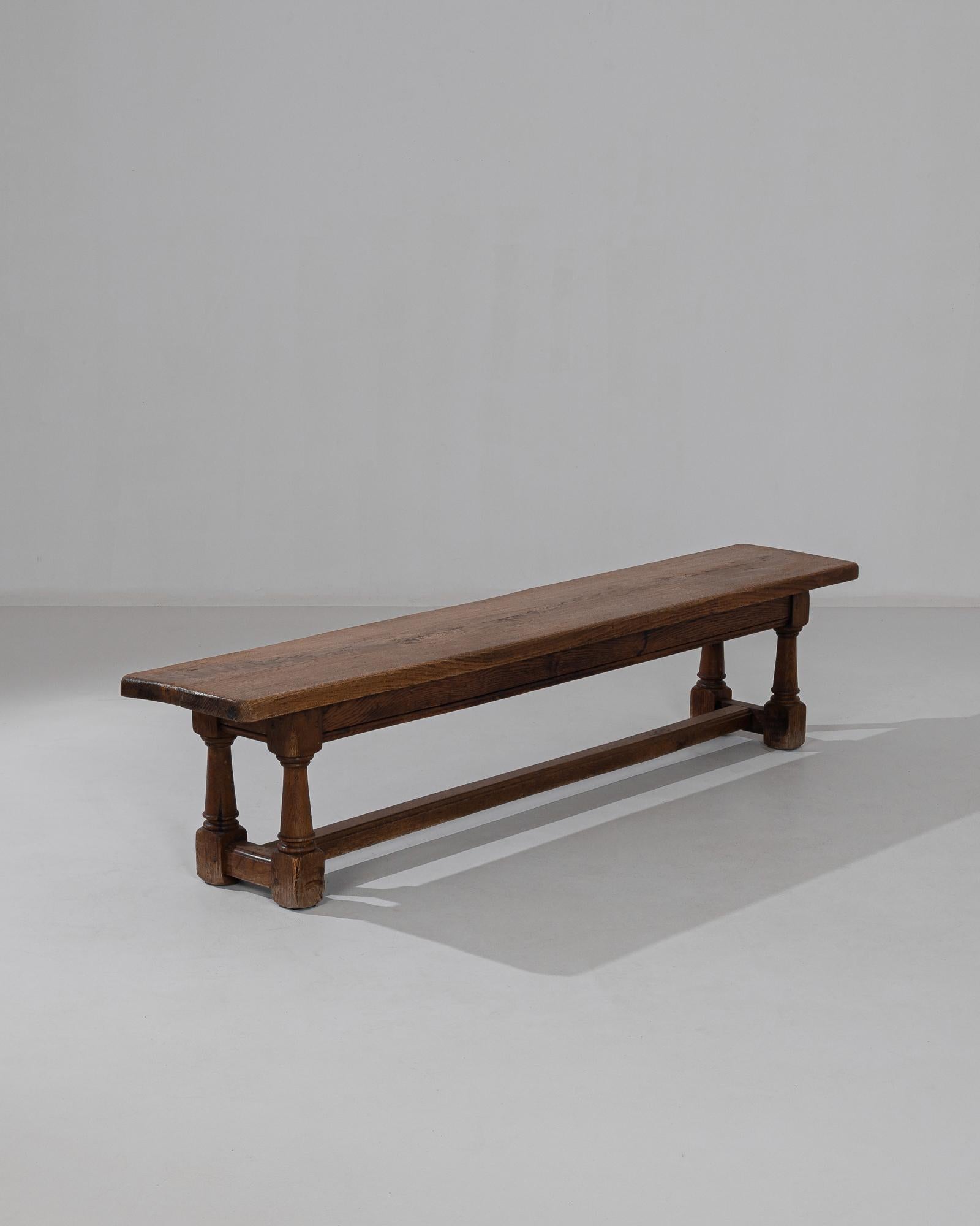 This wooden bench was made in Belgium, circa 1960. A robust construction paired with restrained decoration to bring a quiet dignity, enhanced by the rich tone of the polished oak. A ridge runs along the stretch of the apron, while rings adorn the