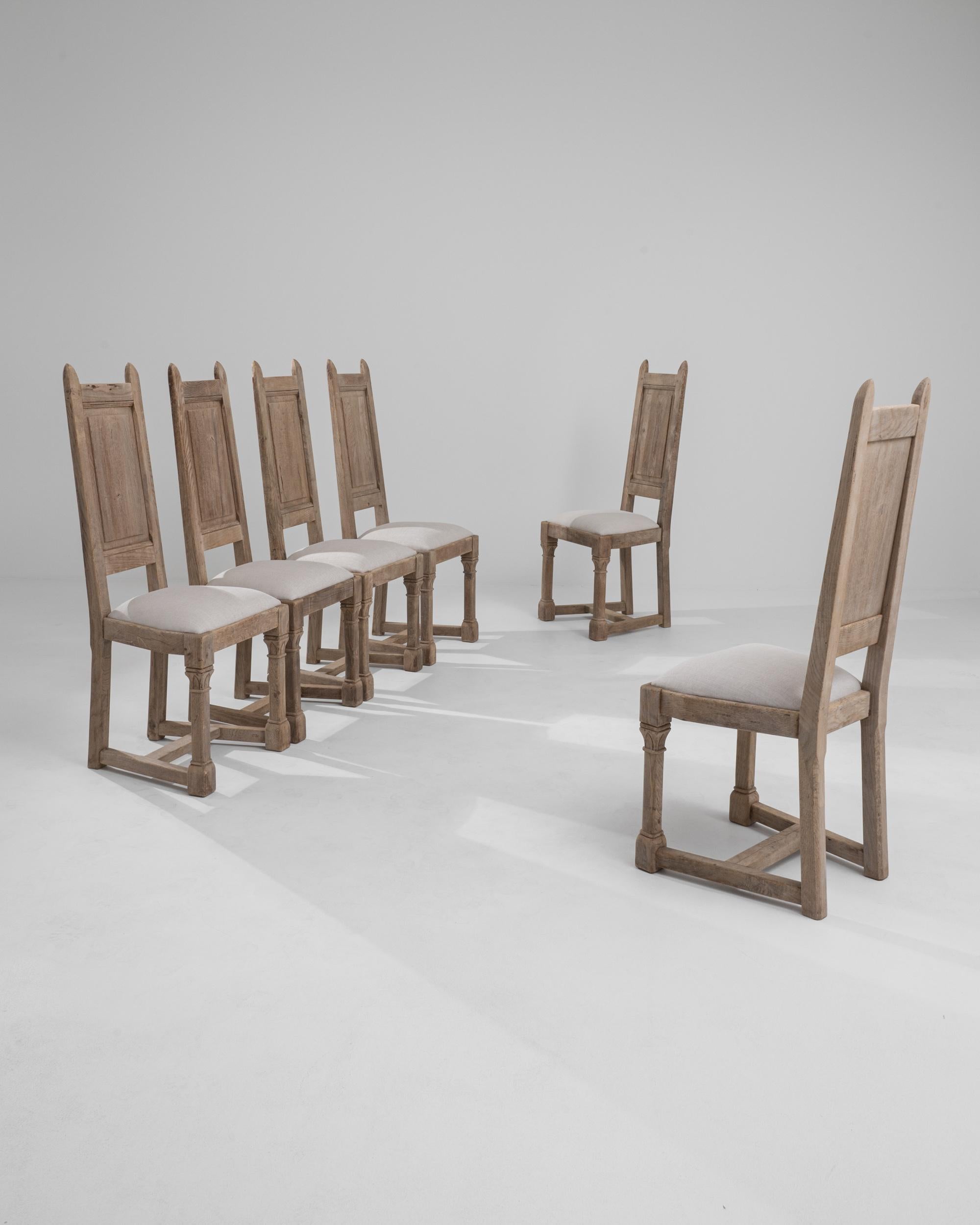 A set of six wooden upholstered dining chairs created in 20th century Belgium. Made in a traditional farmhouse style, this set of chairs imparts an appreciation for the modest and hand-crafted. The fresh off-white upholstery that dawns their seats