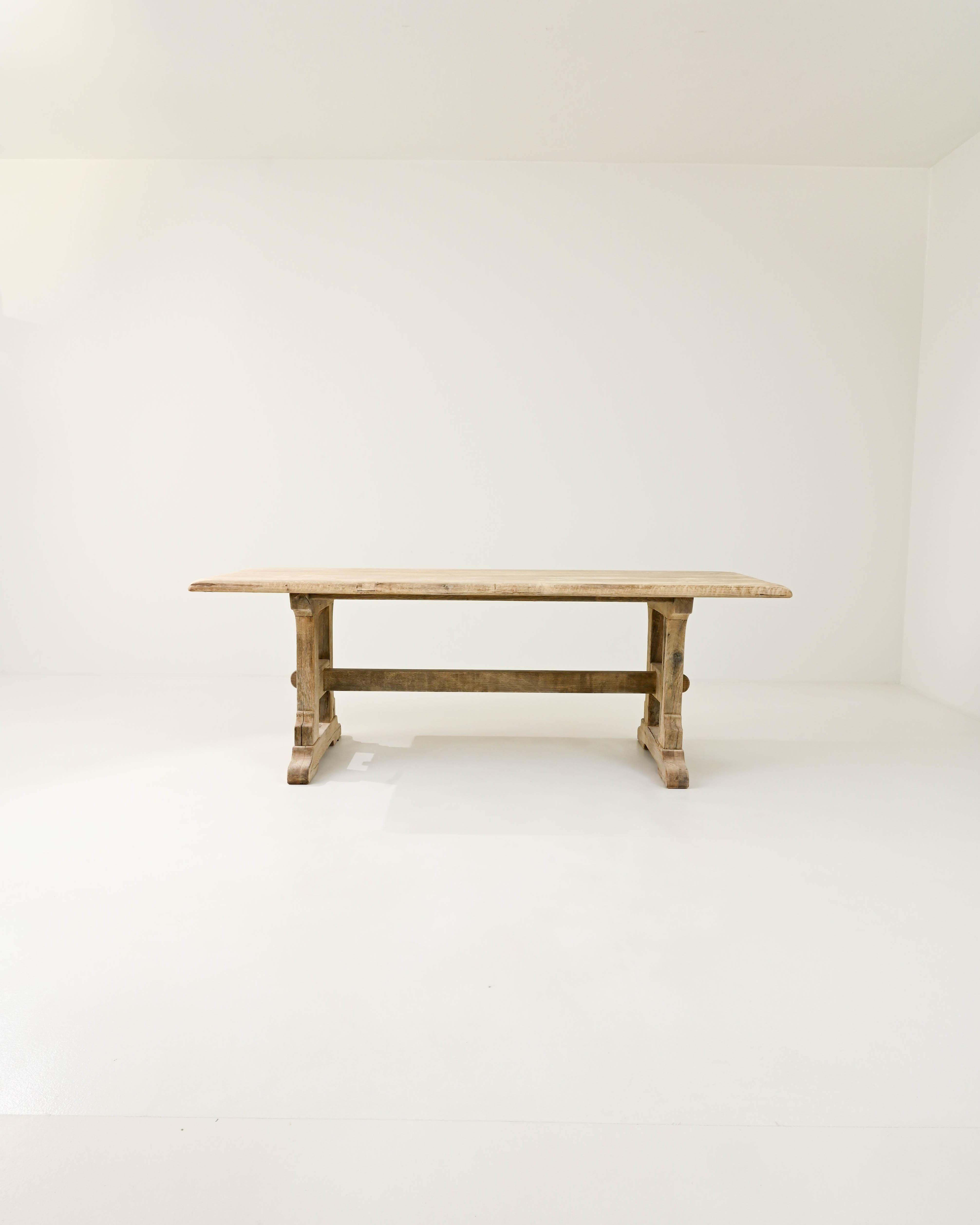 This vintage oak dining table offers a traditional design, beautifully crafted. Hand-built in Belgium in the 20th century, the rectangular tabletop sits atop a trestle base. The simple country silhouette is subtly embellished by the softly carved