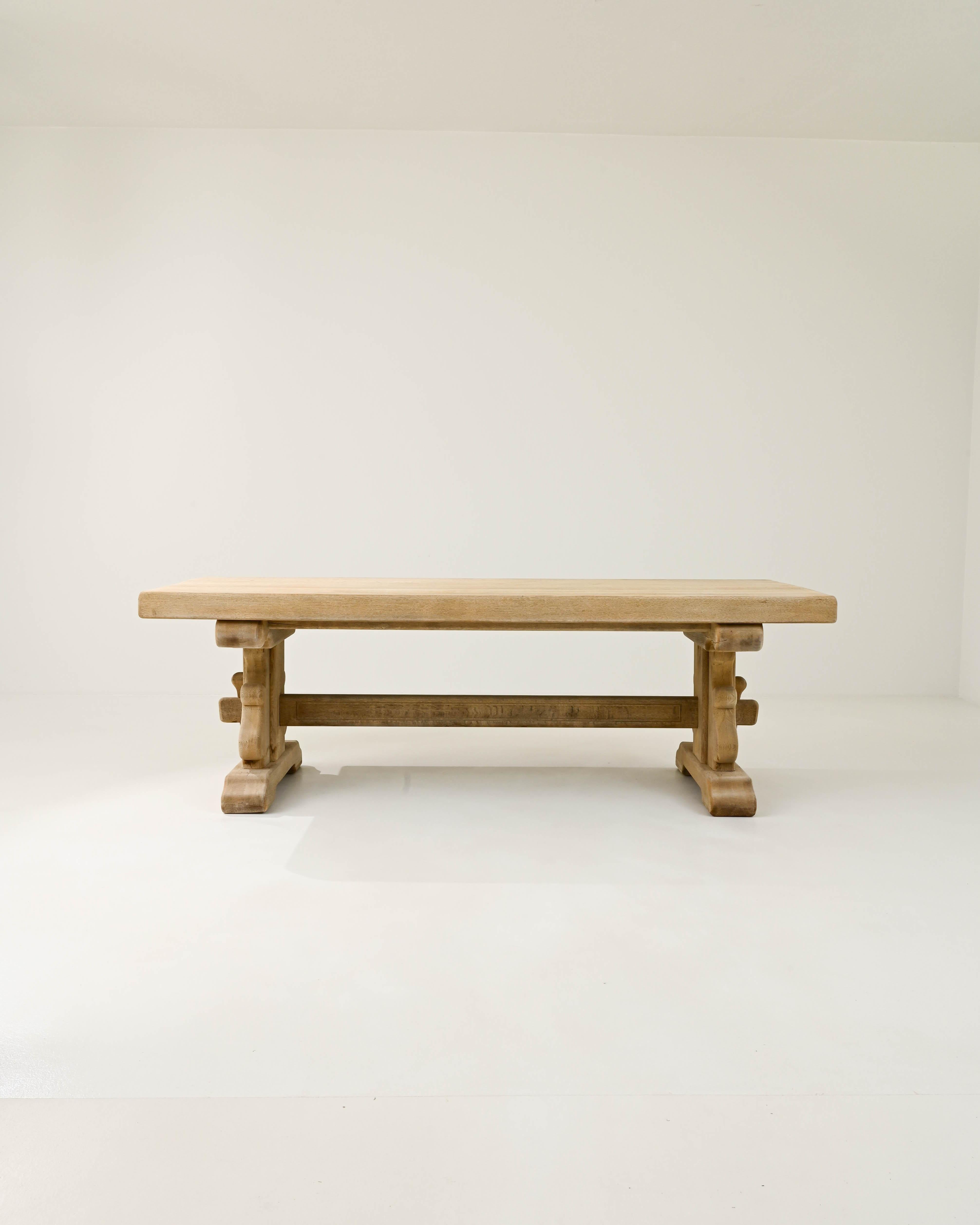 This vintage oak dining table offers a traditional design, beautifully crafted. Hand-built in Belgium in the 20th century, the rectangular table top sits atop a trestle base. The simple country silhouette is subtly embellished by the softly carved