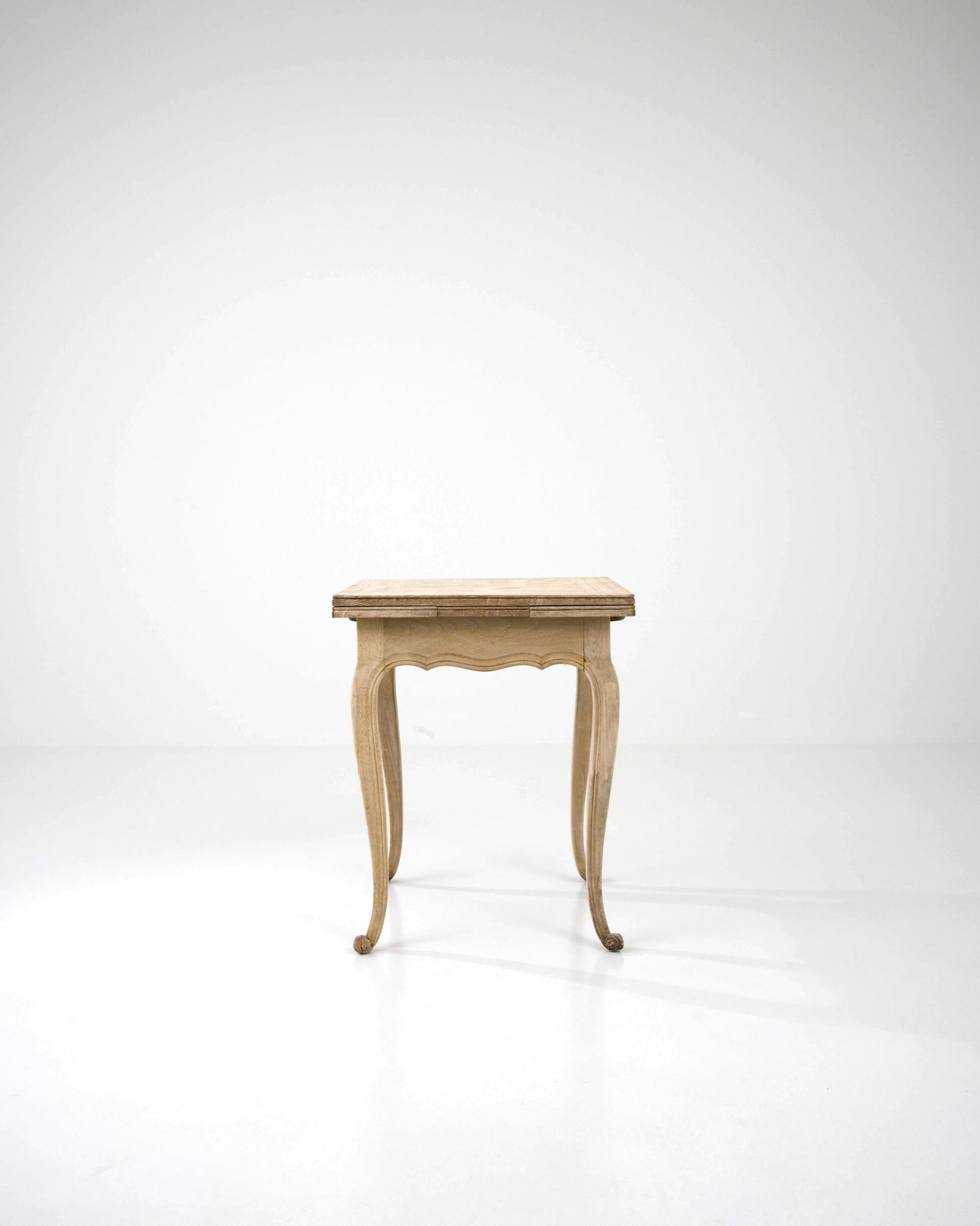 The gentle curvature of the cabriole legs, terminating in delicately carved scroll feet, imparts a graceful silhouette to this vintage table. Hand-crafted in Belgium in the early 20th century, this side table features a square tabletop with