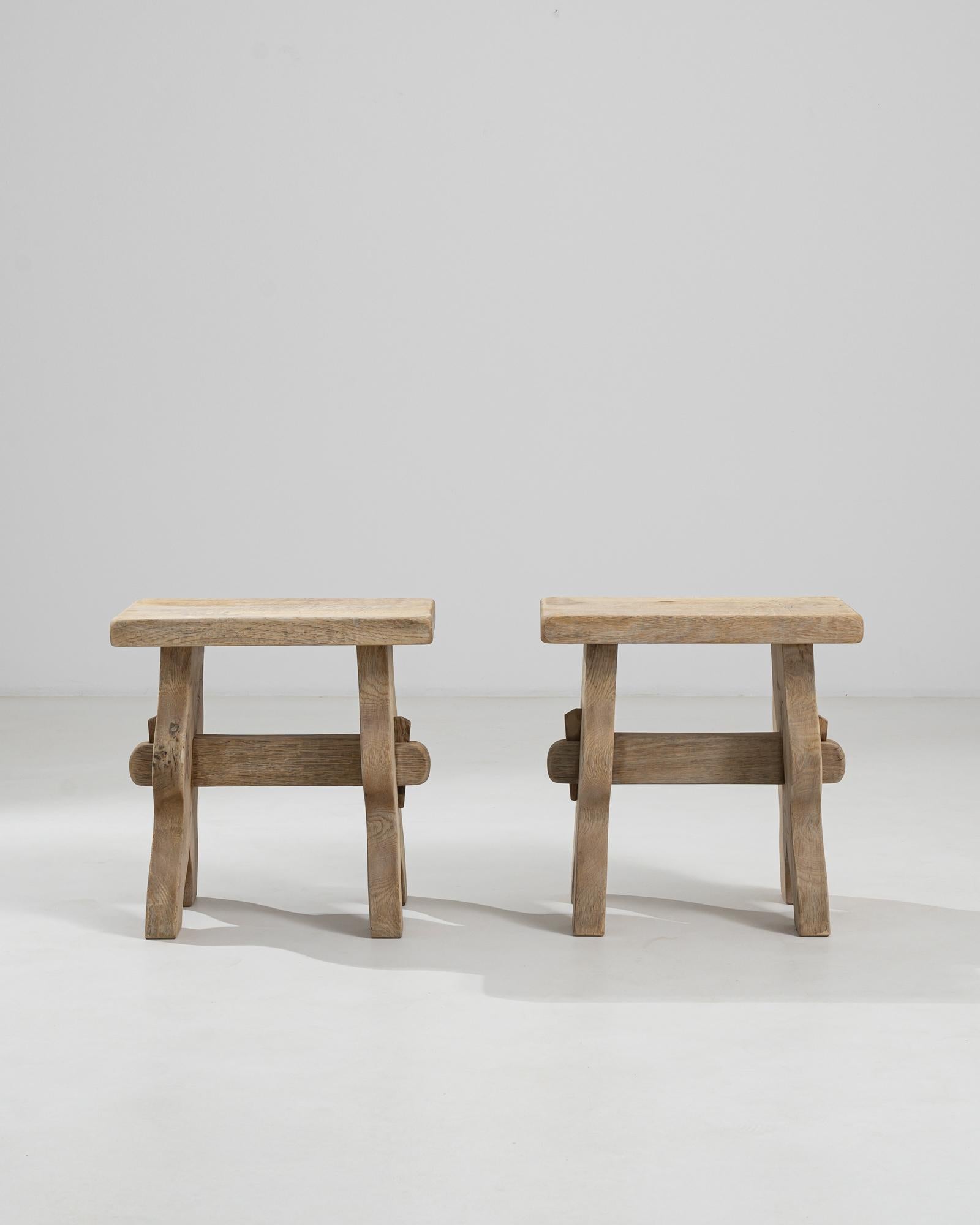 A simple oak stool from Belgium. Restored with a bleached oak finish, the light tone and natural texture recall a countryside locale. Spanned by a trestle and supported by four legs, this simple and practical oak stool accentuates any space with its