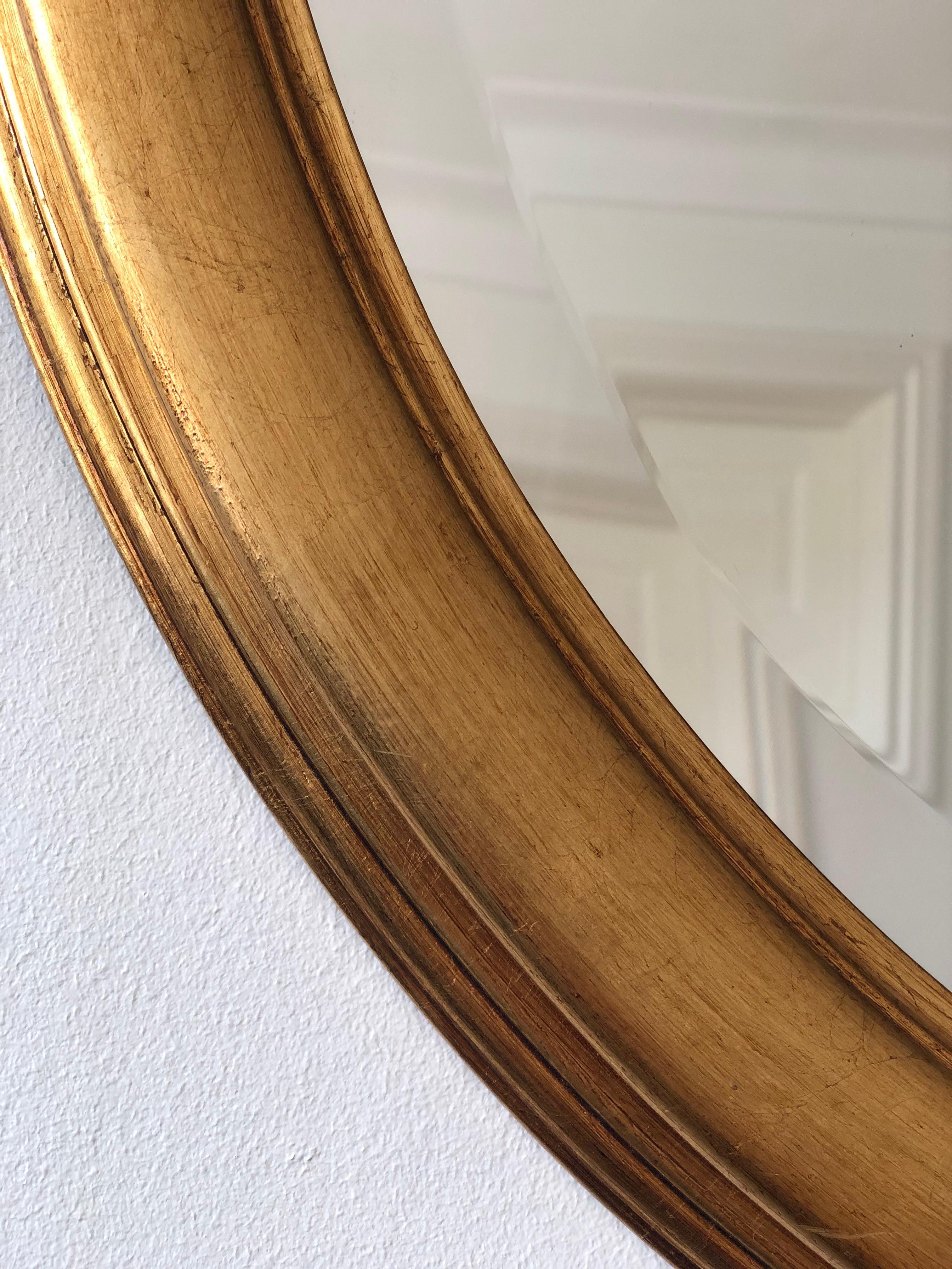 Elegant miroir ovale vintage de Belgique, doté d'un cadre en bois doré sculpté et d'une douce finition dorée. Le verre est biseauté, ce qui apporte une touche raffinée. Une pièce classique à l'attrait intemporel, convenant aussi bien aux intérieurs