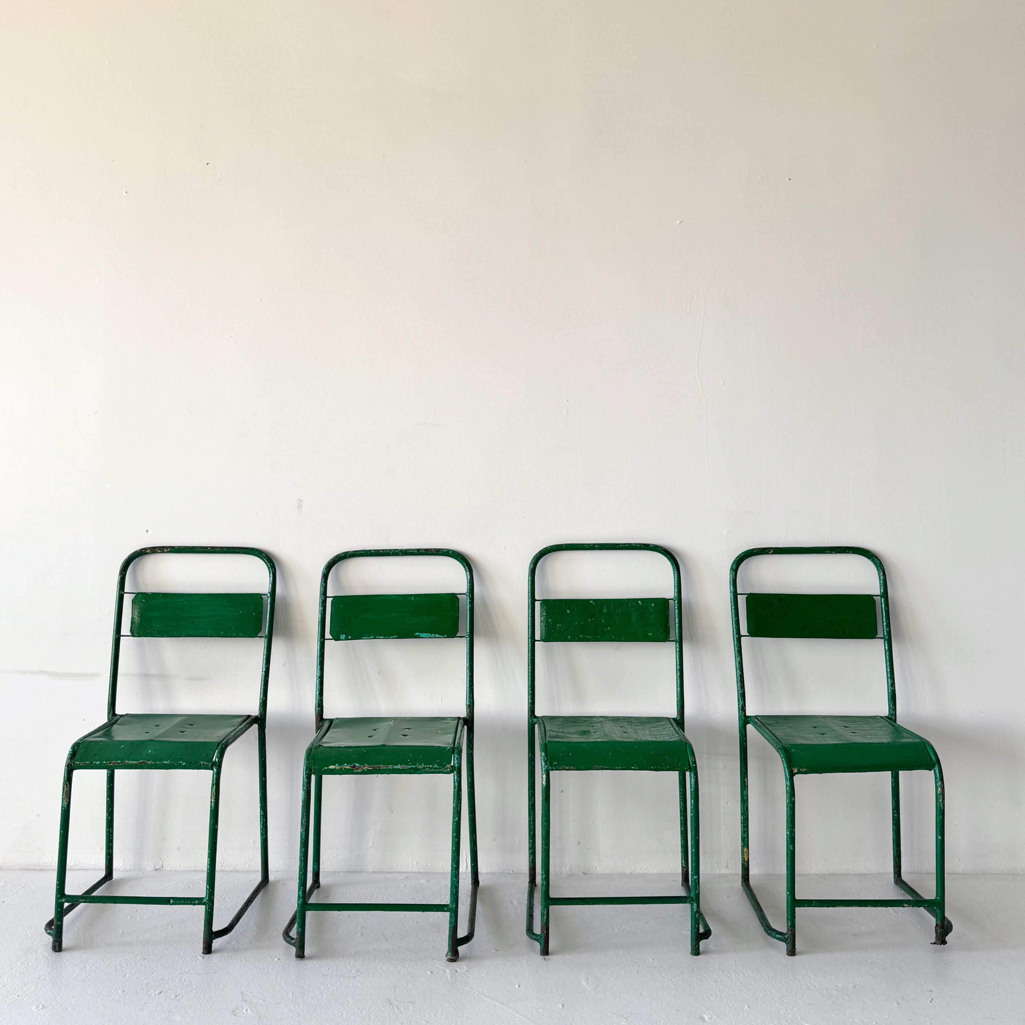 Un conjunto de cuatro sillas de comedor apilables de metal pintado procedentes de una escuela belga. Acabadas en verde con zonas de pátina aguamarina, estas sillas tienen el carácter auténtico de décadas de uso. Prácticas y versátiles, se apilan