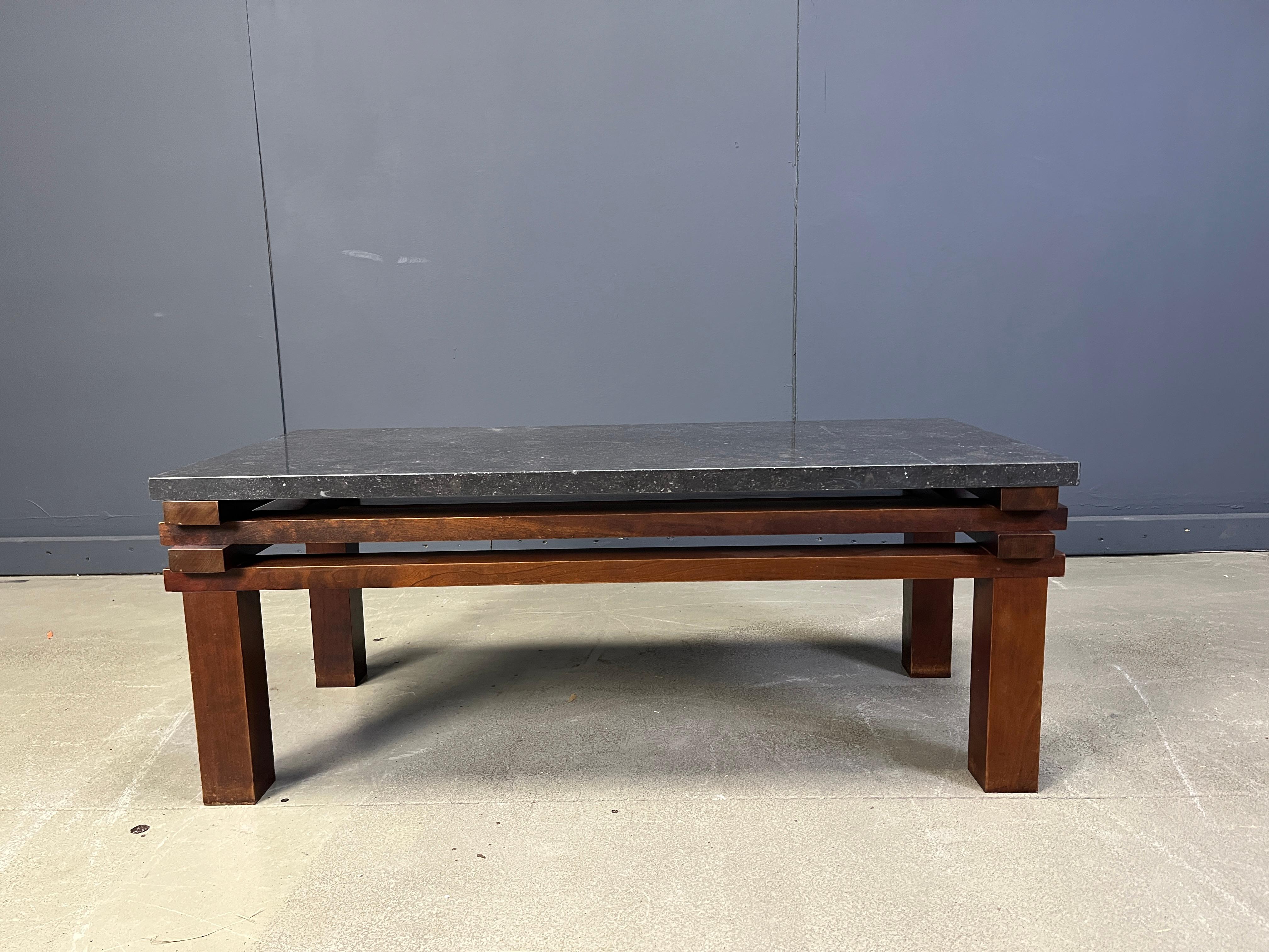 Beautiful wooden coffee table with a black stone table top.

This coffee table has a cool interlocking frame very much inspired by Emiel Veranneman, a famous Belgian Designer.

High wuality wood combined with the black natural stone makes this table