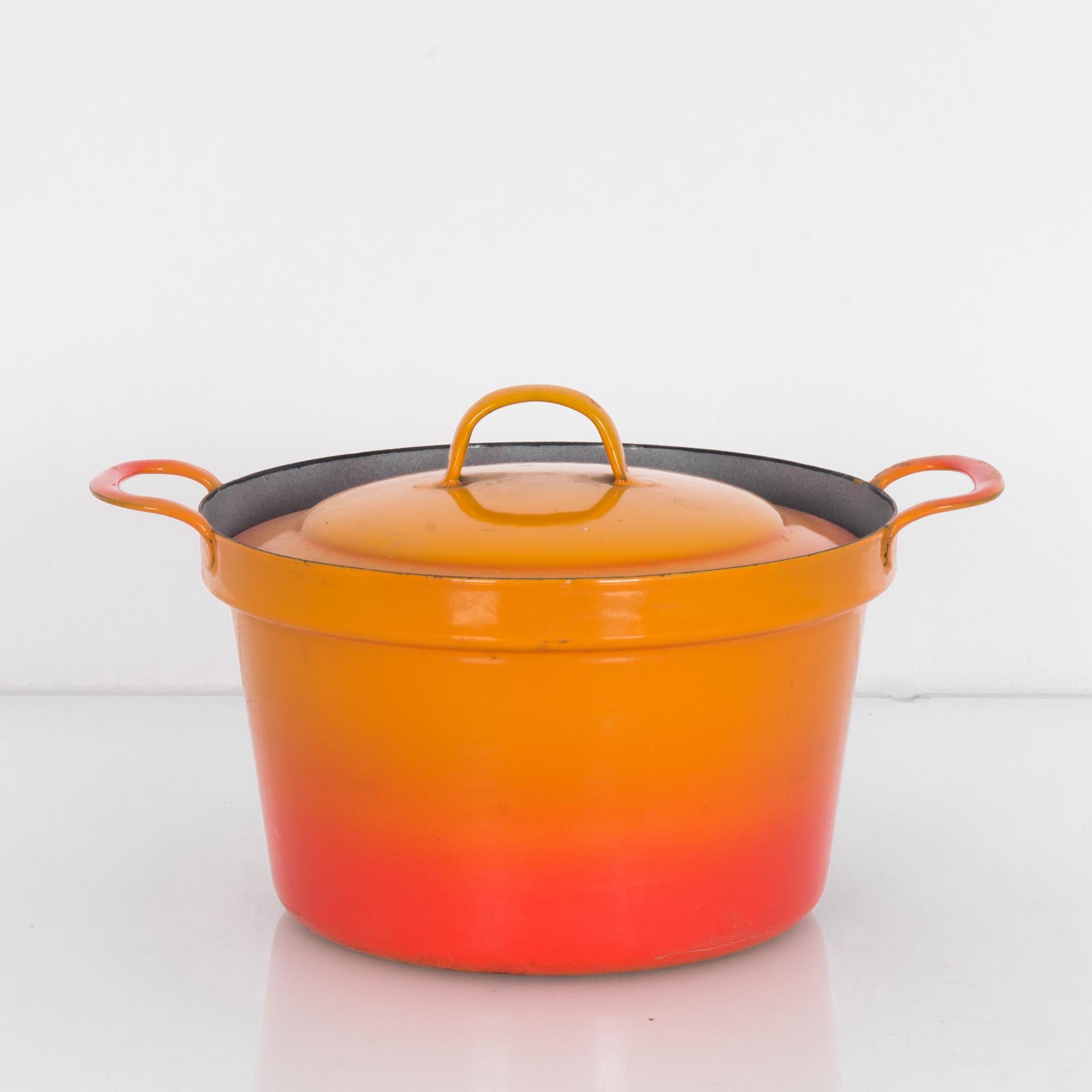 This enamel pot was made in Belgium and features an uplifting yellow-orange gradient. The pot comes with a lid and carrying handles on the sides.