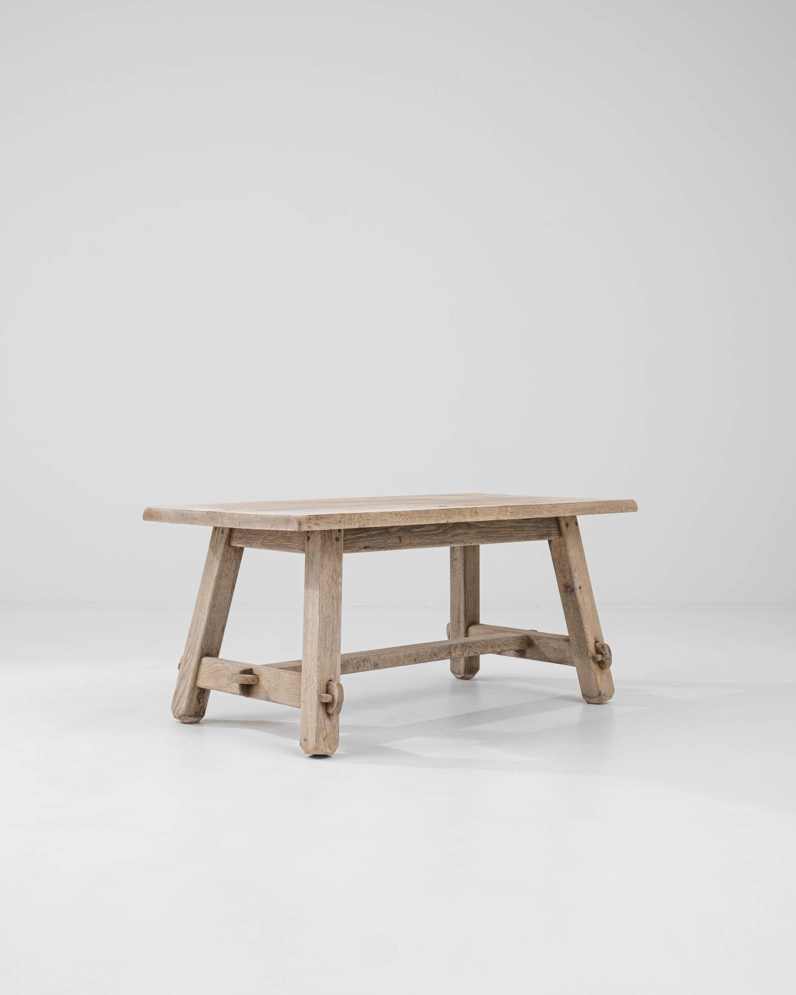 A wooden coffee table created in 20th century Belgium. This charming table exemplifies a practice of lightly altering natural materials to achieve an artful combination of organic and thoughtful design. With an unassuming trestle construction and