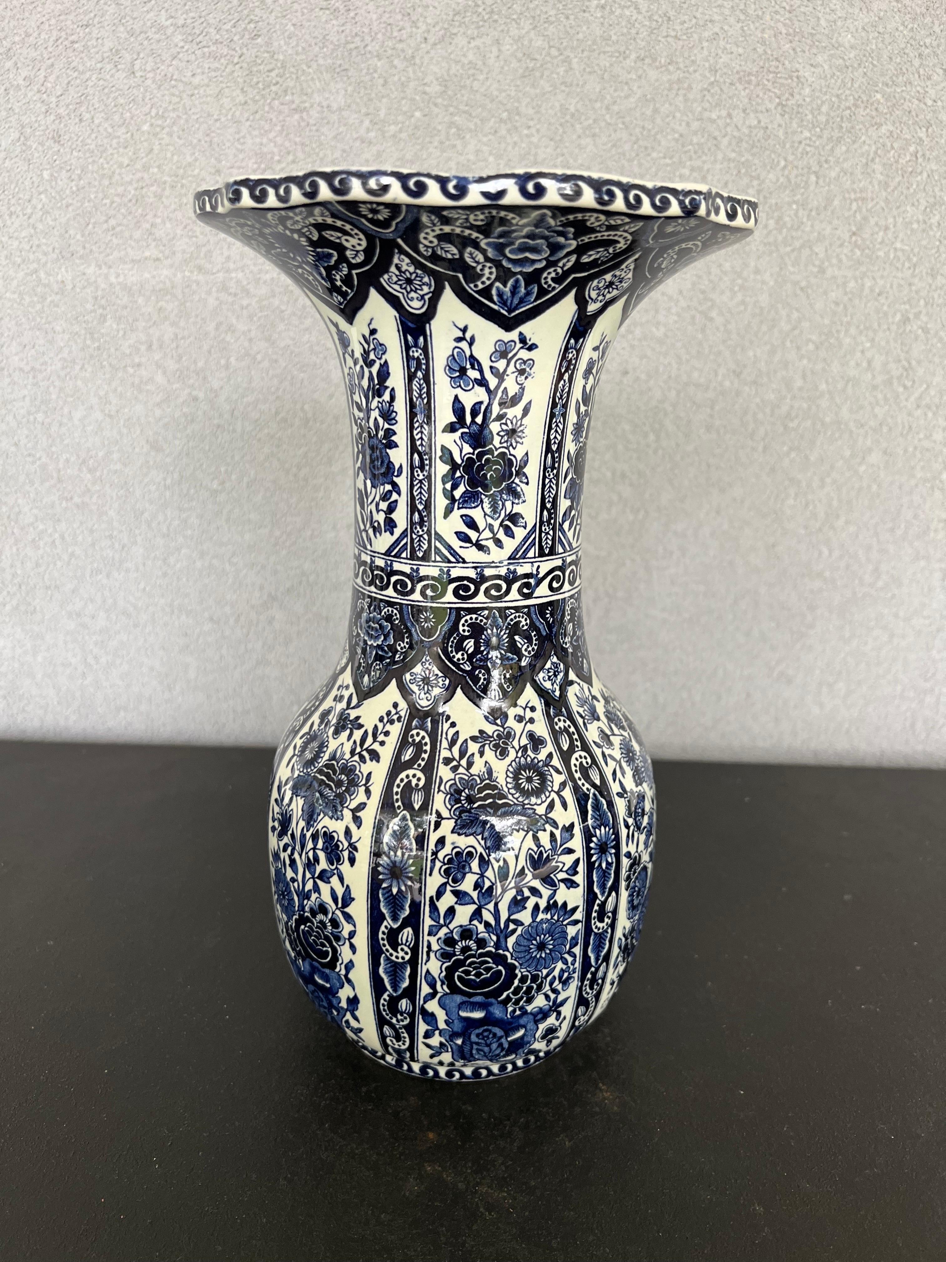 This elegant vintage ceramic Delft vase was created in the Netherlands, circa 1940. Round in shape with a long neck and wide mouth, featuring traditional hand-painted floral decorations. It’s stamped on the bottom, Made by Royal , Delft, Holland.