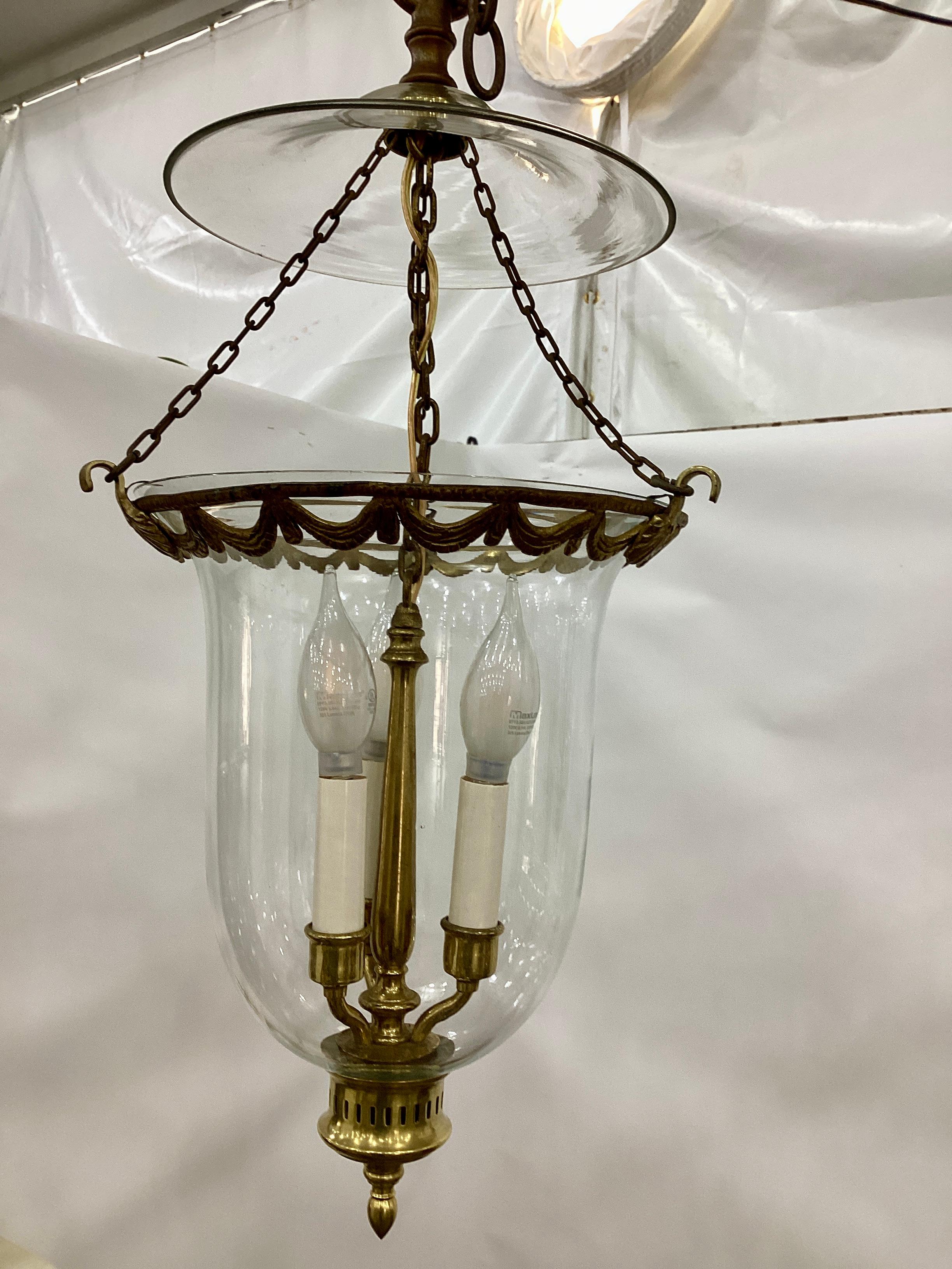 Vintage Bell Jar Lantern with Draped Swag Ring. Top smoke bell is suspended with three chain lengths connected to a ring with draped swag decoration. The bottom of the jar is finished with a brass cap and finial. 
Lantern is wired and in working