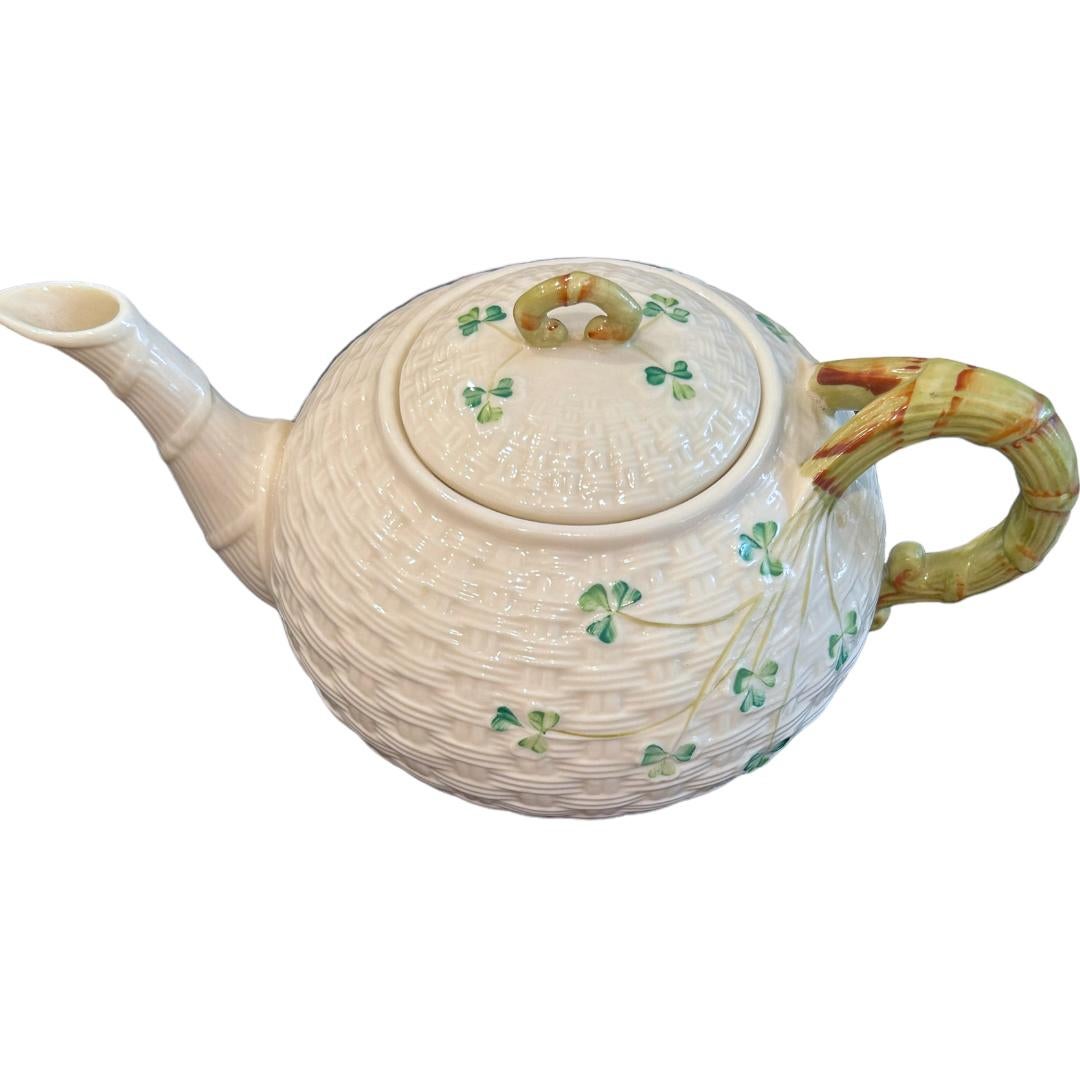 This vintage Belleek teapot, made from 1980-1992, is a charming addition to any collection.  The delicate basketweave design and shamrock embellishments are characteristic of the renowned brand.  It comes with a lid and has the 7th brown mark,