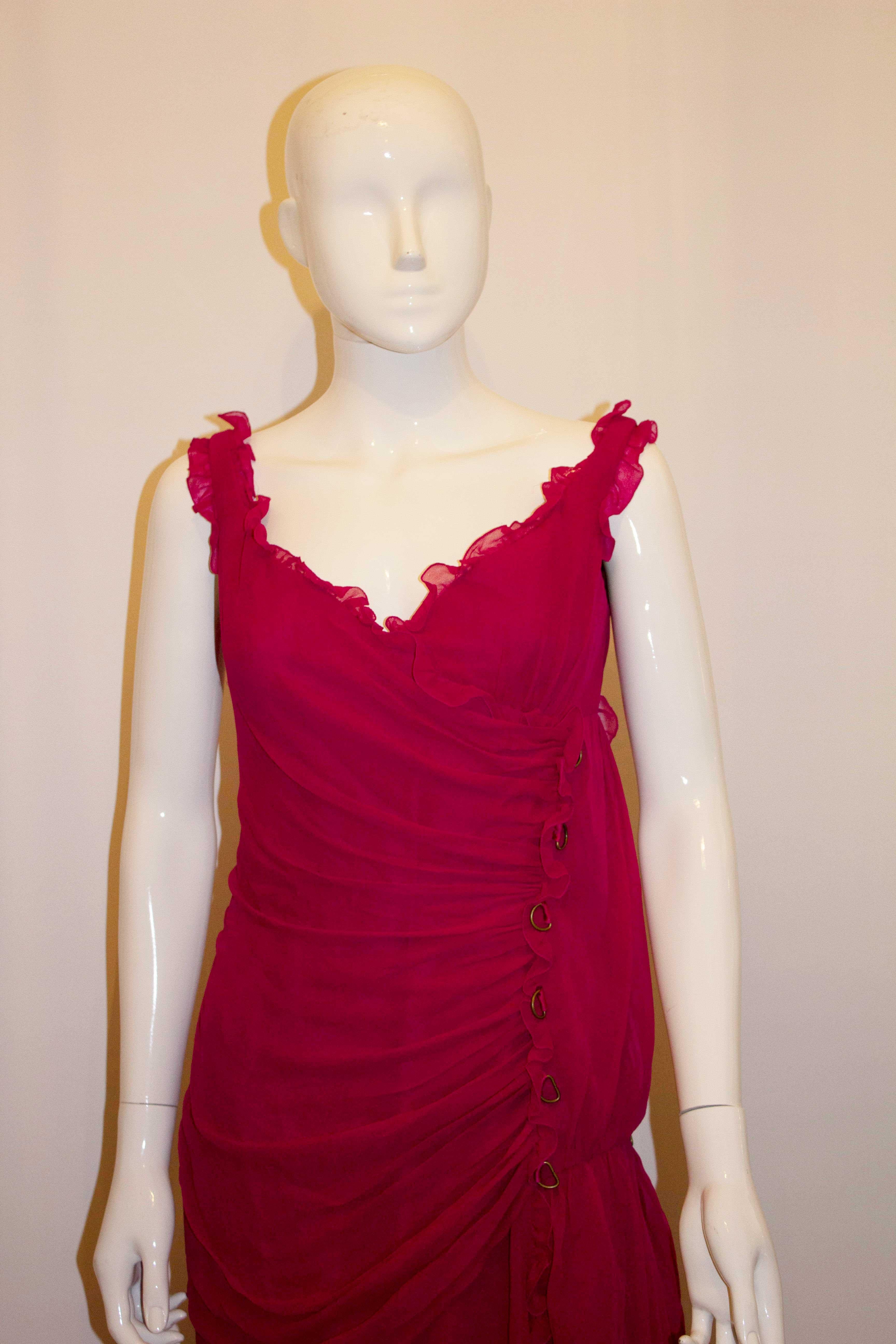 A headturning vintage  silk gown by Bellville Sassoon. In a bright pink silk , the dress has a v neckline and backline with frill detail and layers. The bodice is boned and the dress has a side zip opening. It has industrial style ring decoration on