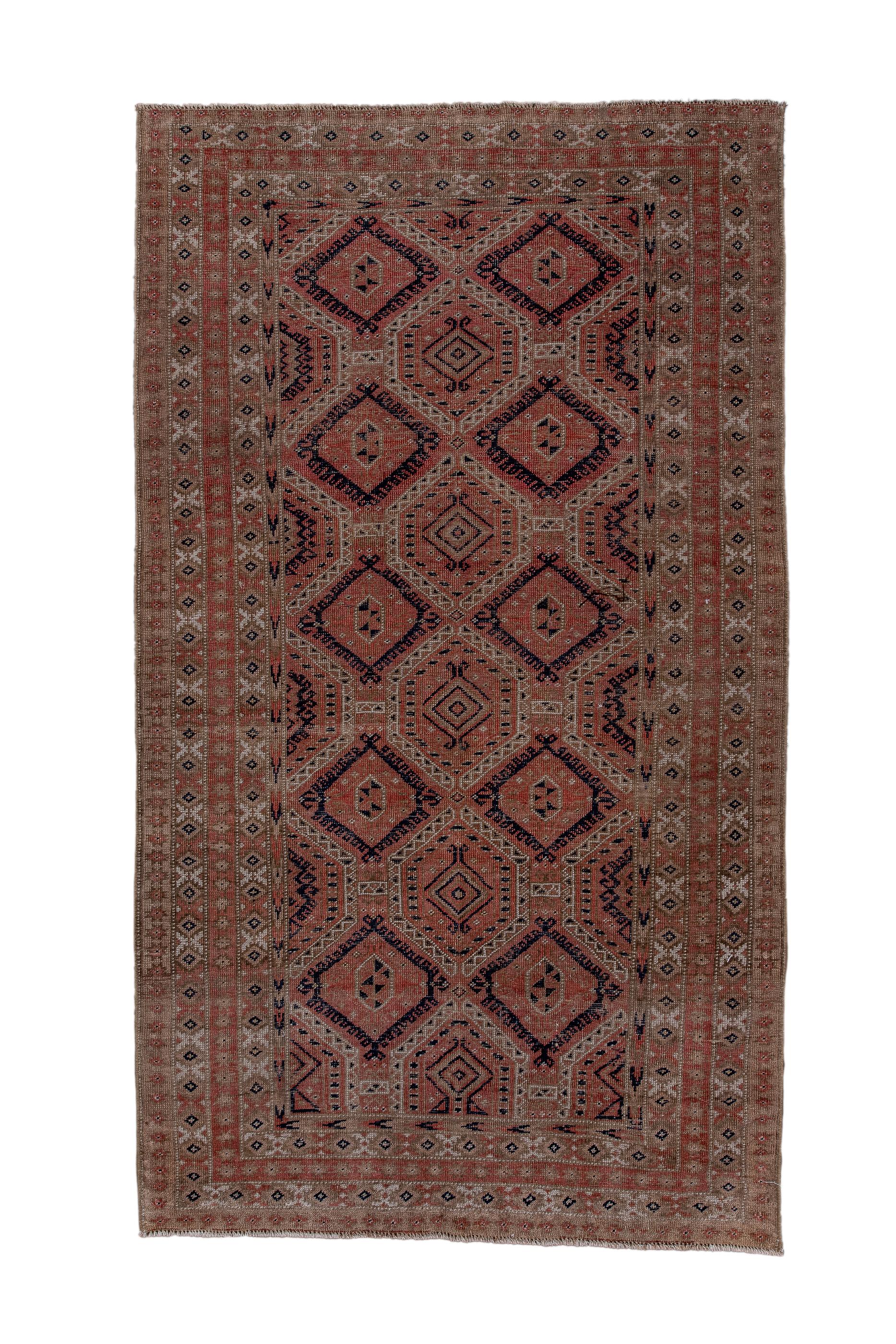 This nomadic rug shows an allover pattern of large, stepped hexagons alternating rows with stepped dark blue diamonds, all on a coral field. Pattern is not balanced vertically.  Two major borders with X and lozenge repeat patterns. Moderate/medium