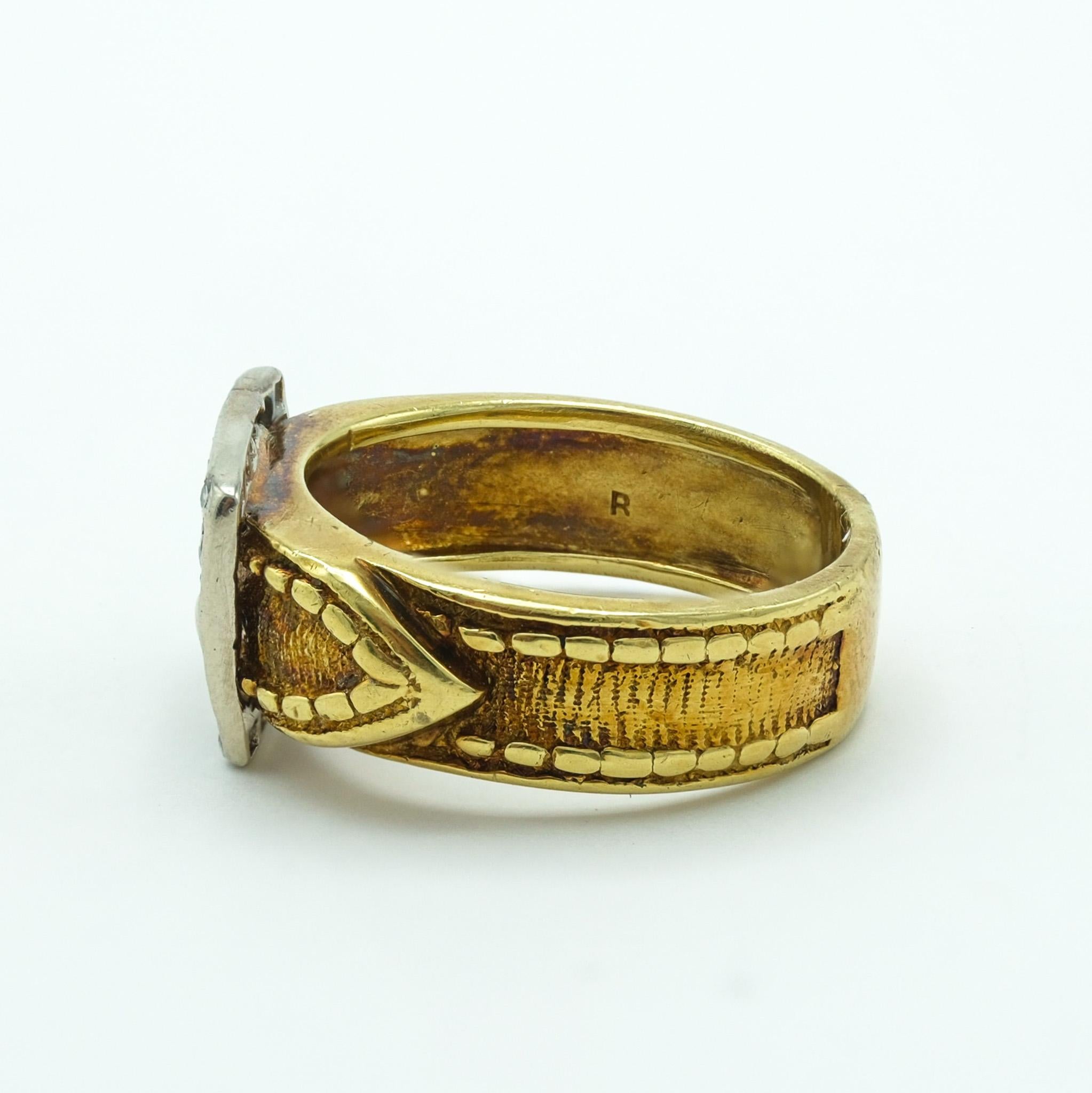 This vintage buckle ring is a testament to exquisite craftsmanship, forged from a blend of 18 karat yellow and white gold. The white gold buckle is lined with 17 round diamonds. The ring carries the graceful patina, hinting at its history and the