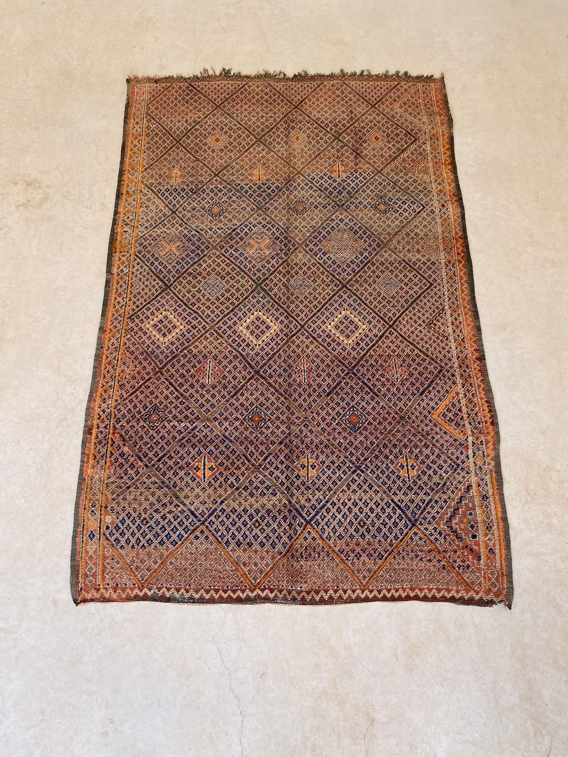 This beautiful vintage Beni Mguild rug is a great find! The main background color is a mix of terracotta and soft orange with intricate designs -mostly tiny diamonds- in cream, orange and navy blue. The pattern is a multiplied diamonds and the whole