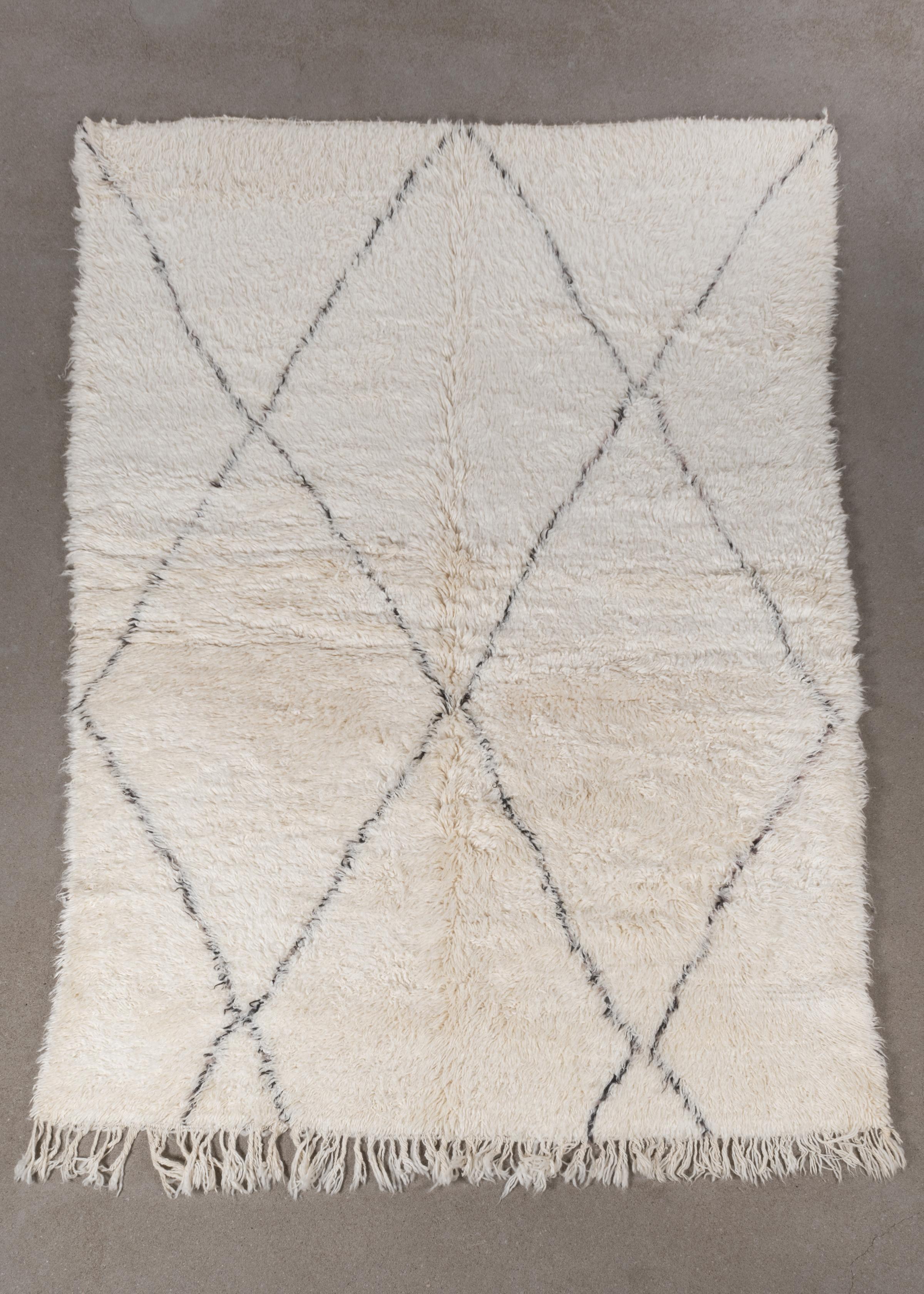 This vintage Beni Ourain rug is personally selected in Morocco and has a soft ivory color due to the wool's natural color and are accompanied by dark grey stripes. The rugs are named after the Berber village 'Beni Ourain' in the mid-Atlas mountain