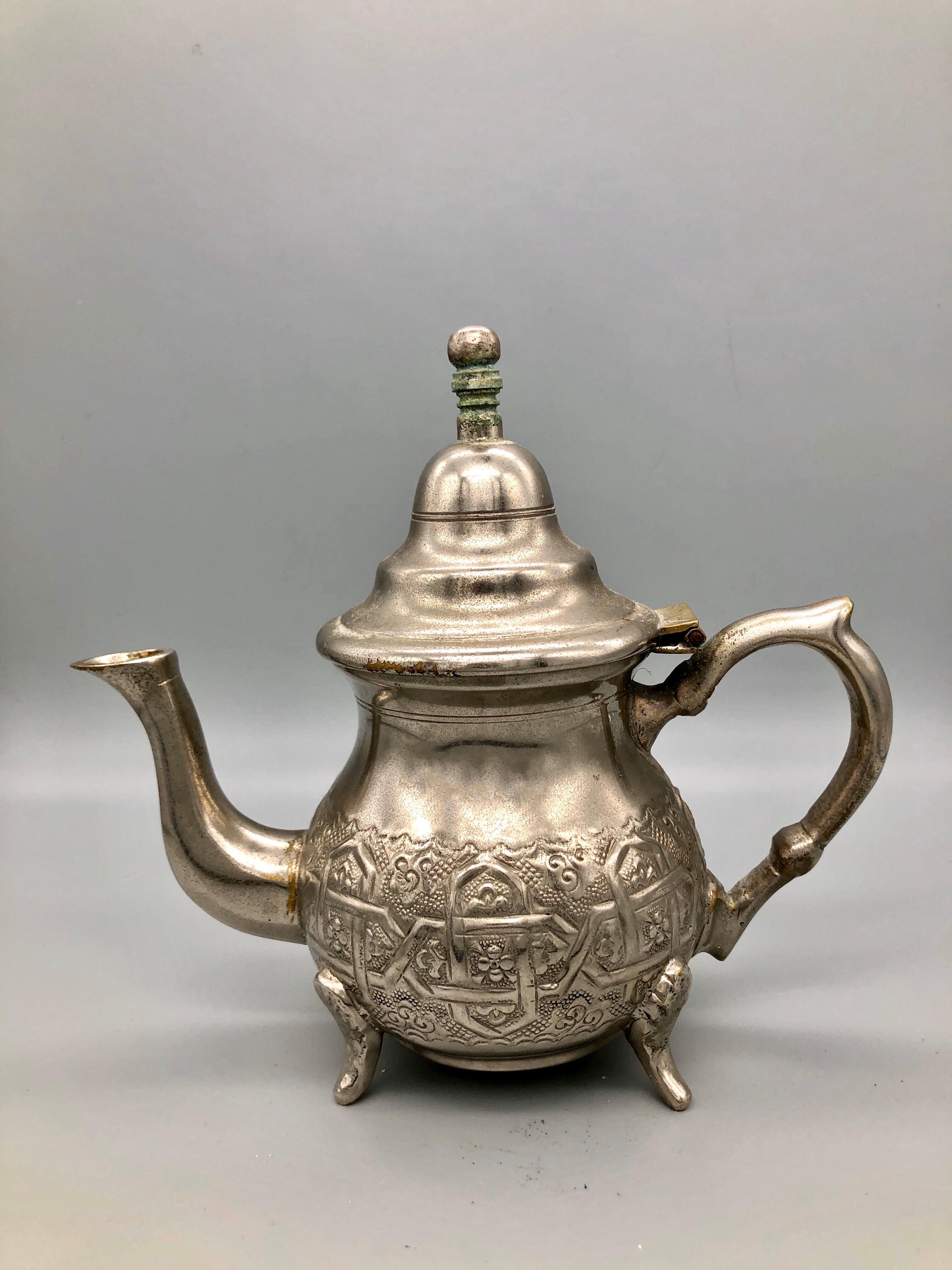 This lovely little silver plated teapot is perfect for a personal pot of Moroccan mint tea. Handmade by the renowned Bennani Frères silversmiths of Fes, Morocco. Intricate repousse geometric design with flowers and spirals, with four claw feet.