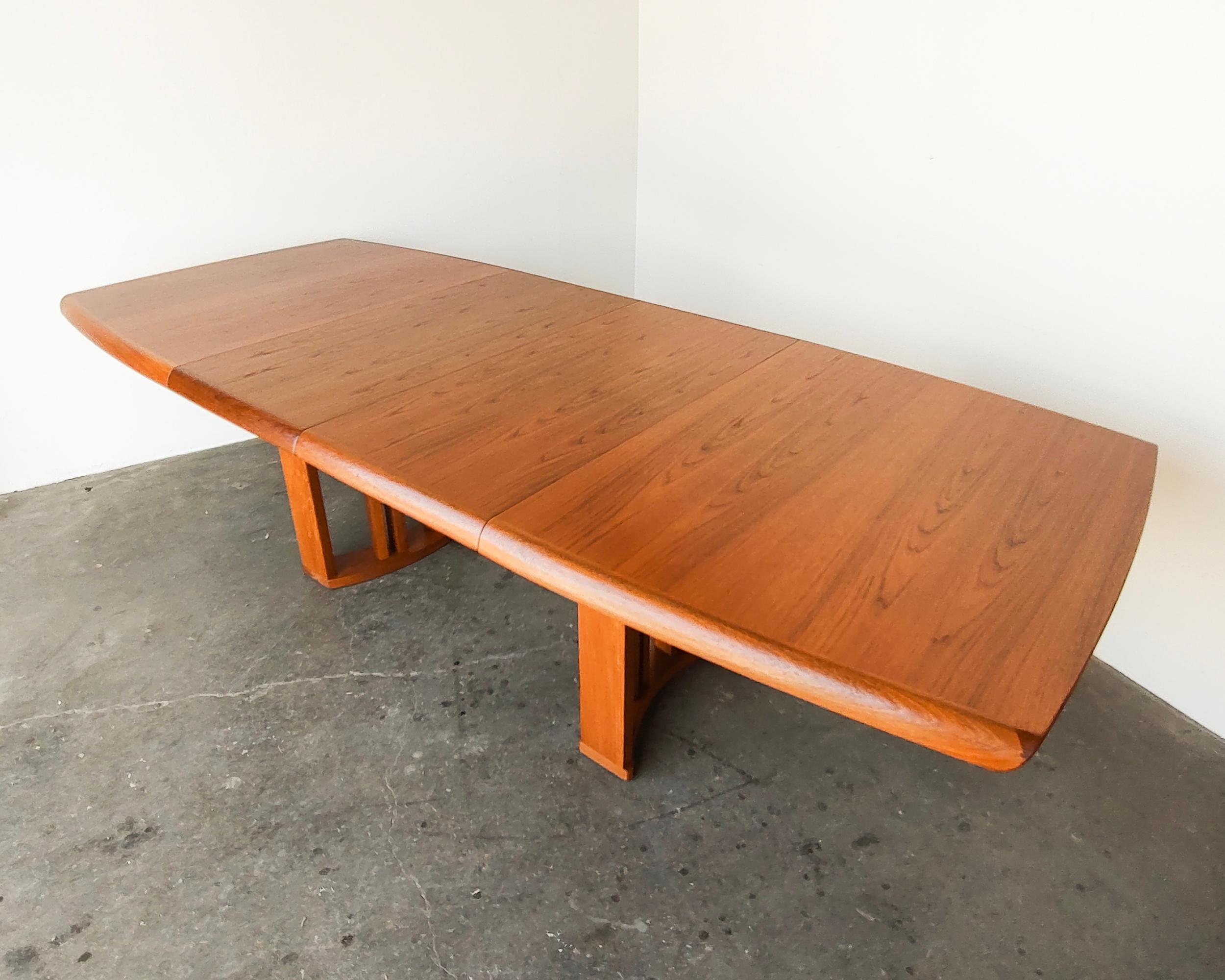 Vintage teak wood expandable dining table by Benny Linden. Slatted double pedestal legs with tapered rectangular top. Solid wood angled edge. Each end pulls apart while the legs remain in place, revealing two hidden leaves. The table expands from