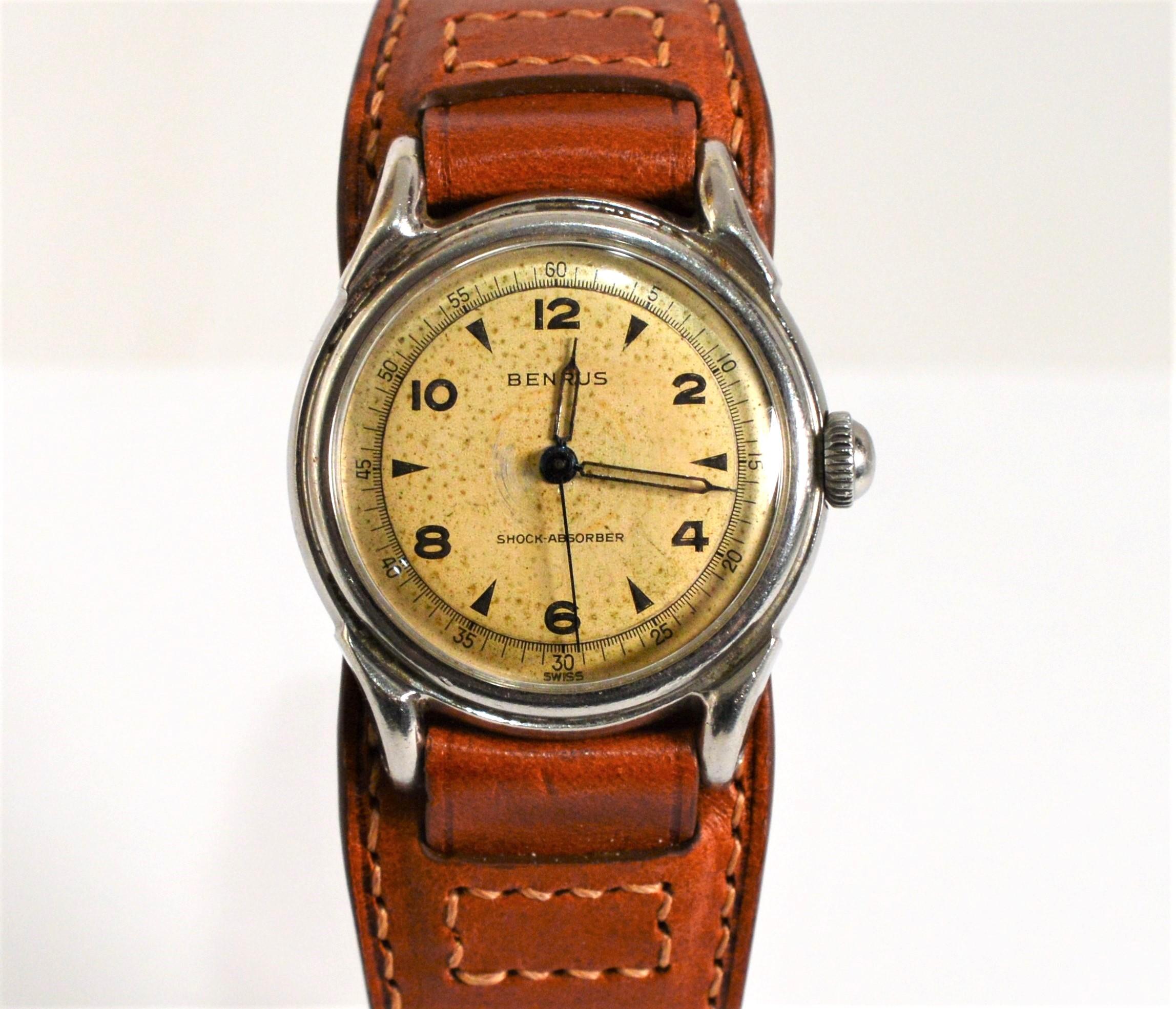 Enjoy this neat post WWII Benrus Military BH-11 Style Steel Men's Wrist Watch. In case size 31.5mm, the dial has a combination of Arabic numerals and matchstick markers with a sweep second hand.  The metallic blue hands and second hand add a bit of