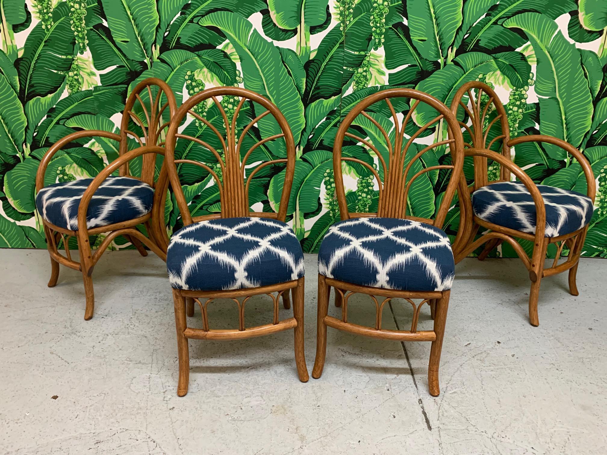 Set of four vintage rattan dining chairs includes two side chairs and two arm chairs. Upholstered in blue and white modern fabric. Very good condition with only very minor imperfections consistent with age. Side chairs measure 16.5