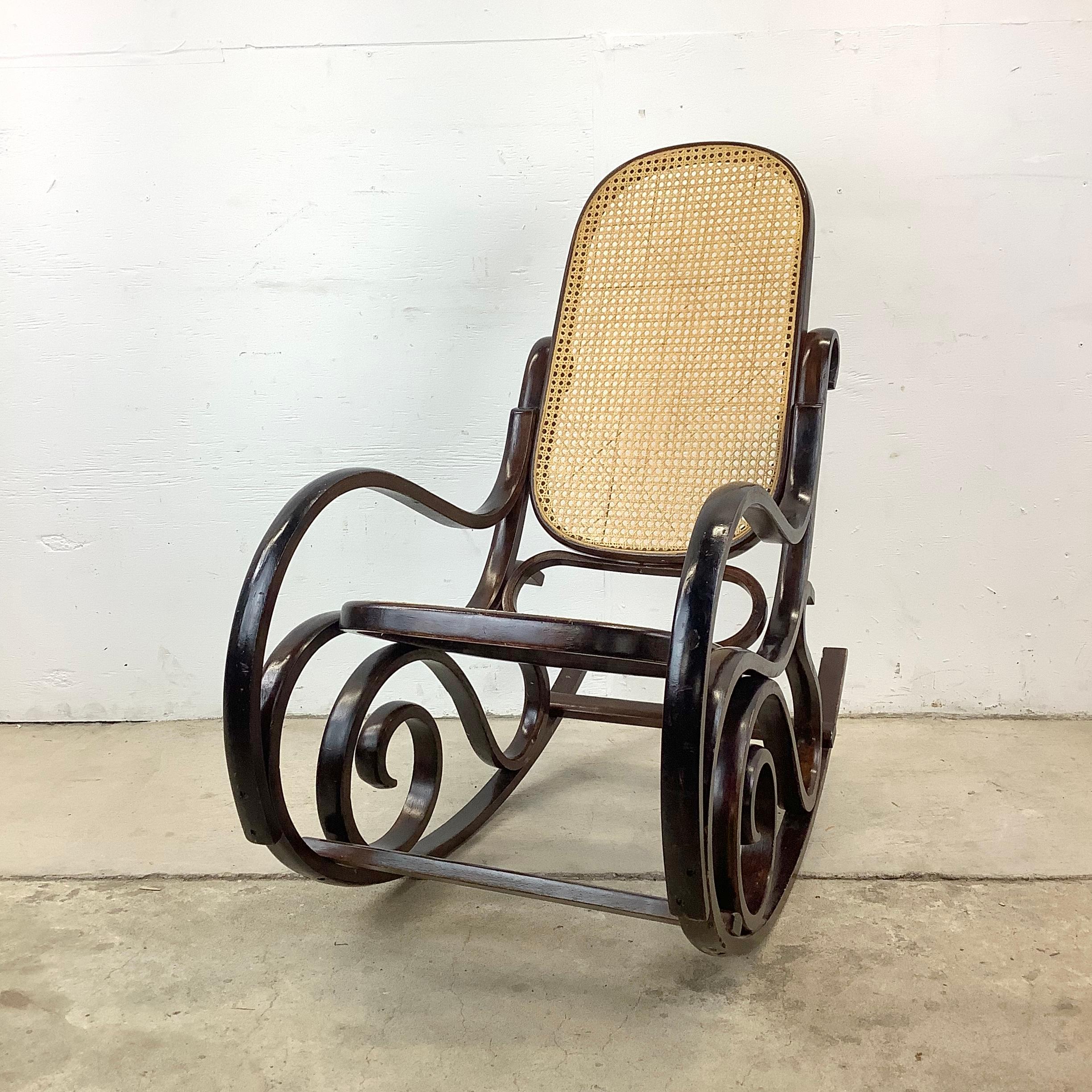 This Vintage Cane Seat Rocking Chair with Bentwood frame is inspired by the timeless elegance of early Thonet furniture. Crafted with meticulous attention to detail, this rocking chair pays homage to the iconic designs of Michael Thonet, renowned