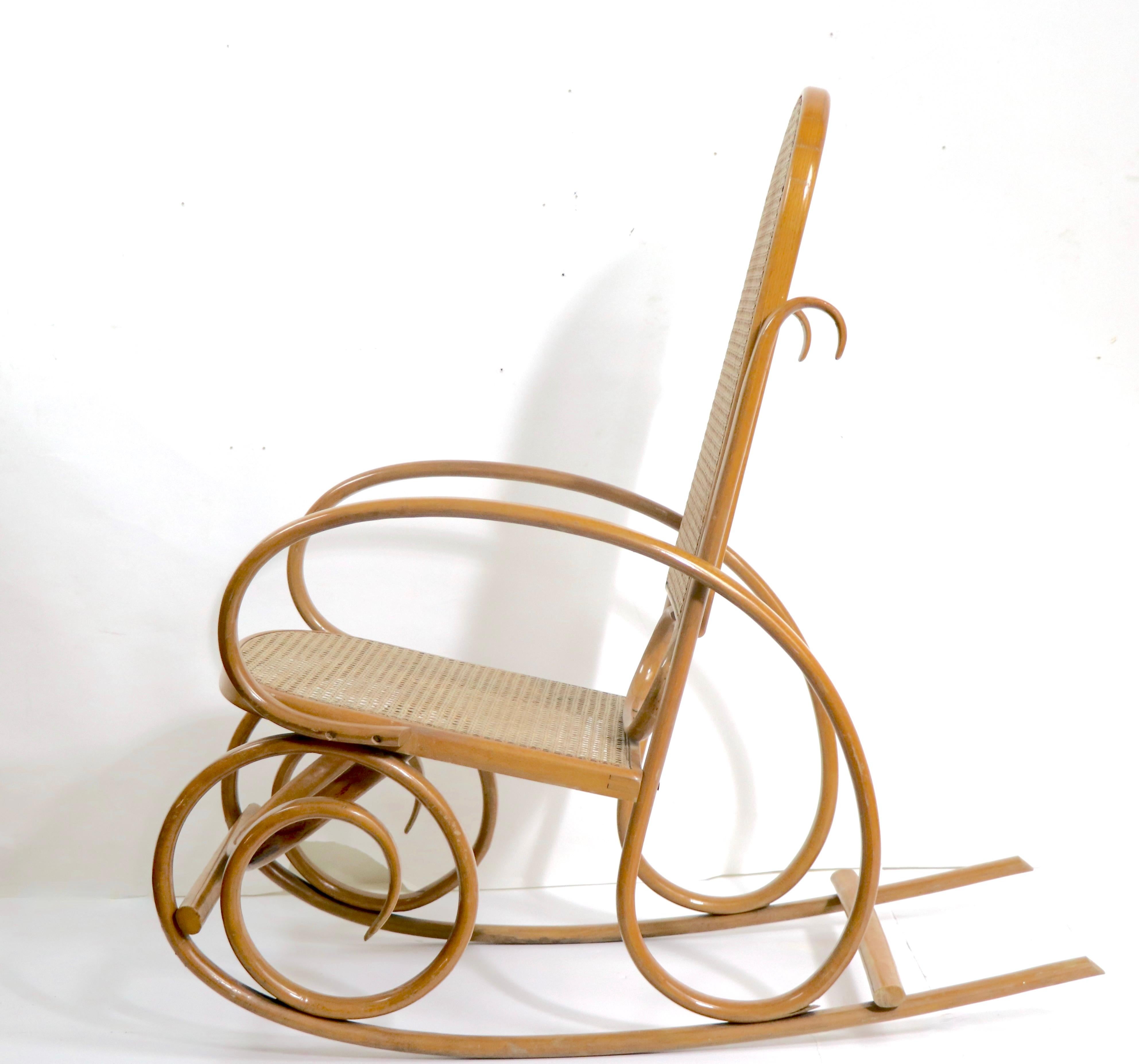Ungewöhnlicher Schaukelstuhl aus Bugholz und Rohr, im Stil des Wiener Secessionismus, wahrscheinlich Mitte des 20. Jahrhunderts, Thonet - made in USA, unsigniert. Der Stuhl ist etwas kleiner als die häufig auf dem Markt anzutreffende Version. Dieses