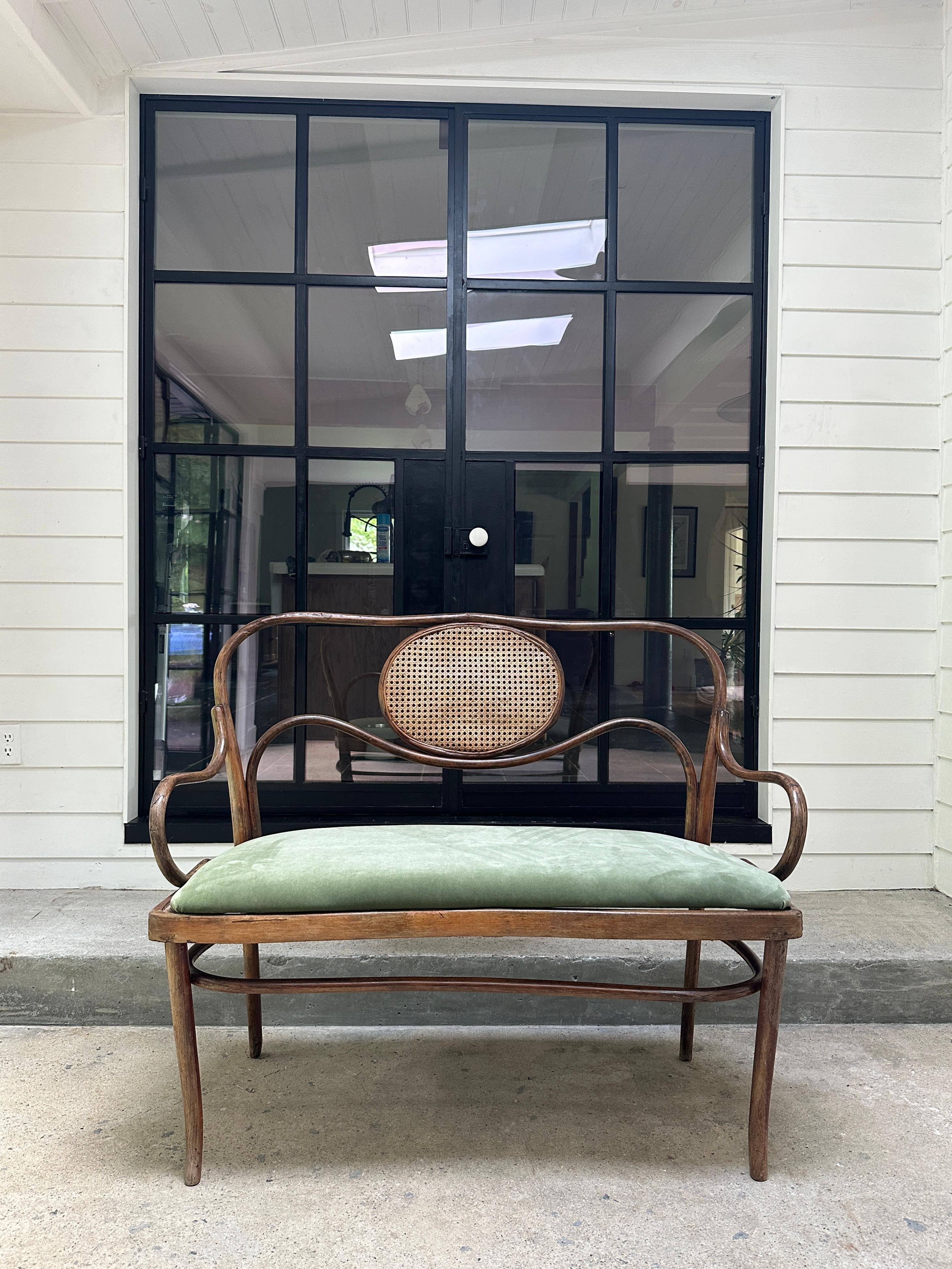 Vintage bench attributed to German/Austrian furniture company ‘Thonet’ in steam curved featuring a cane seat. 

Original bench featured cane seat that was later modified with the addition of a seat recently upholstered in green velvet.

46ʺW ×