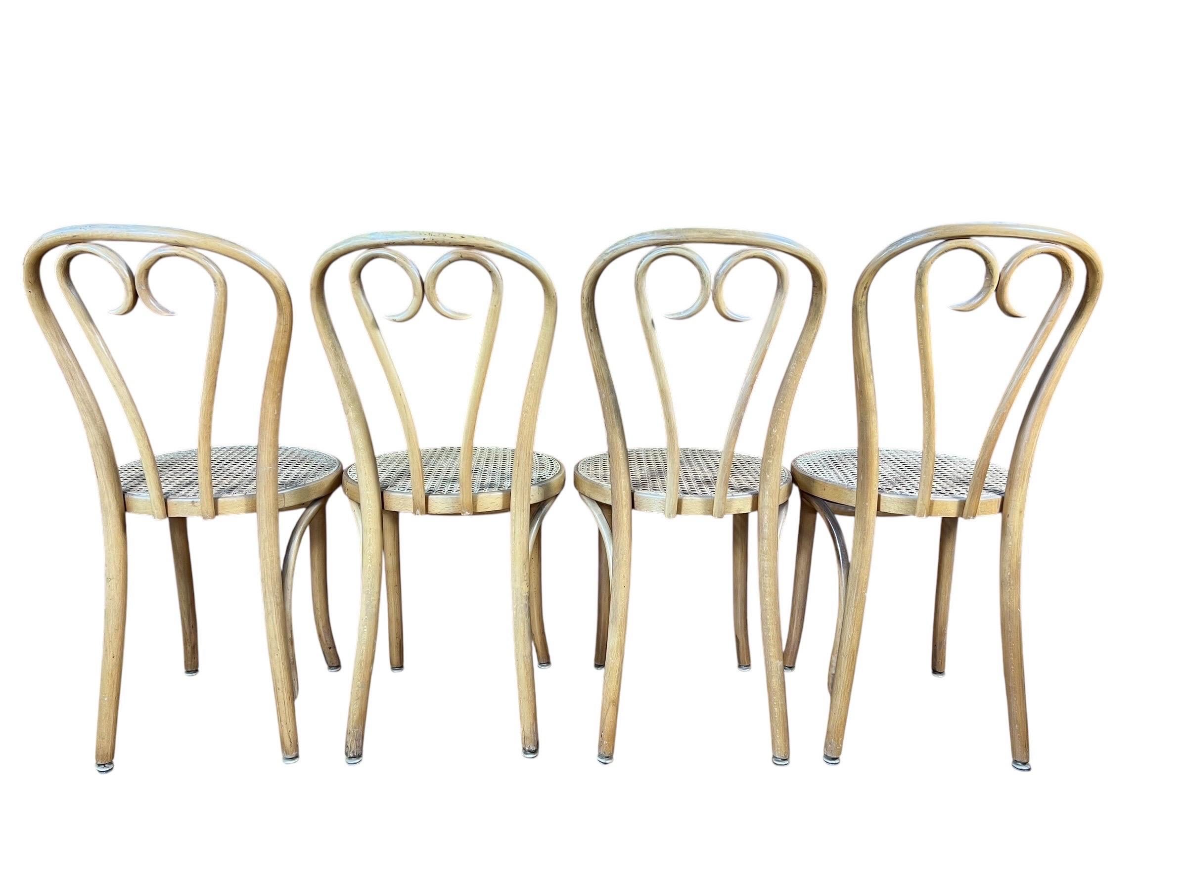 Grande set di quattro sedie vintage in stile Thonet in legno curvato con sedili in canna, le sedie sono state prodotte in Europa.