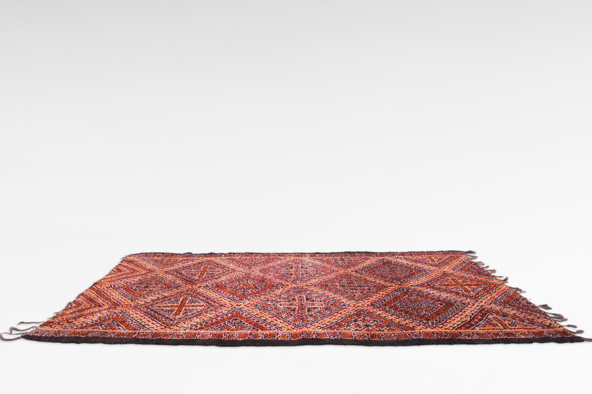 This vintage Boujad rug, hailing from Morocco, is a masterfully crafted work of art, perfect for enhancing any interior space. It radiates warmth and vitality with its dynamic red-orange color palette, which effortlessly draws the eye and enlivens