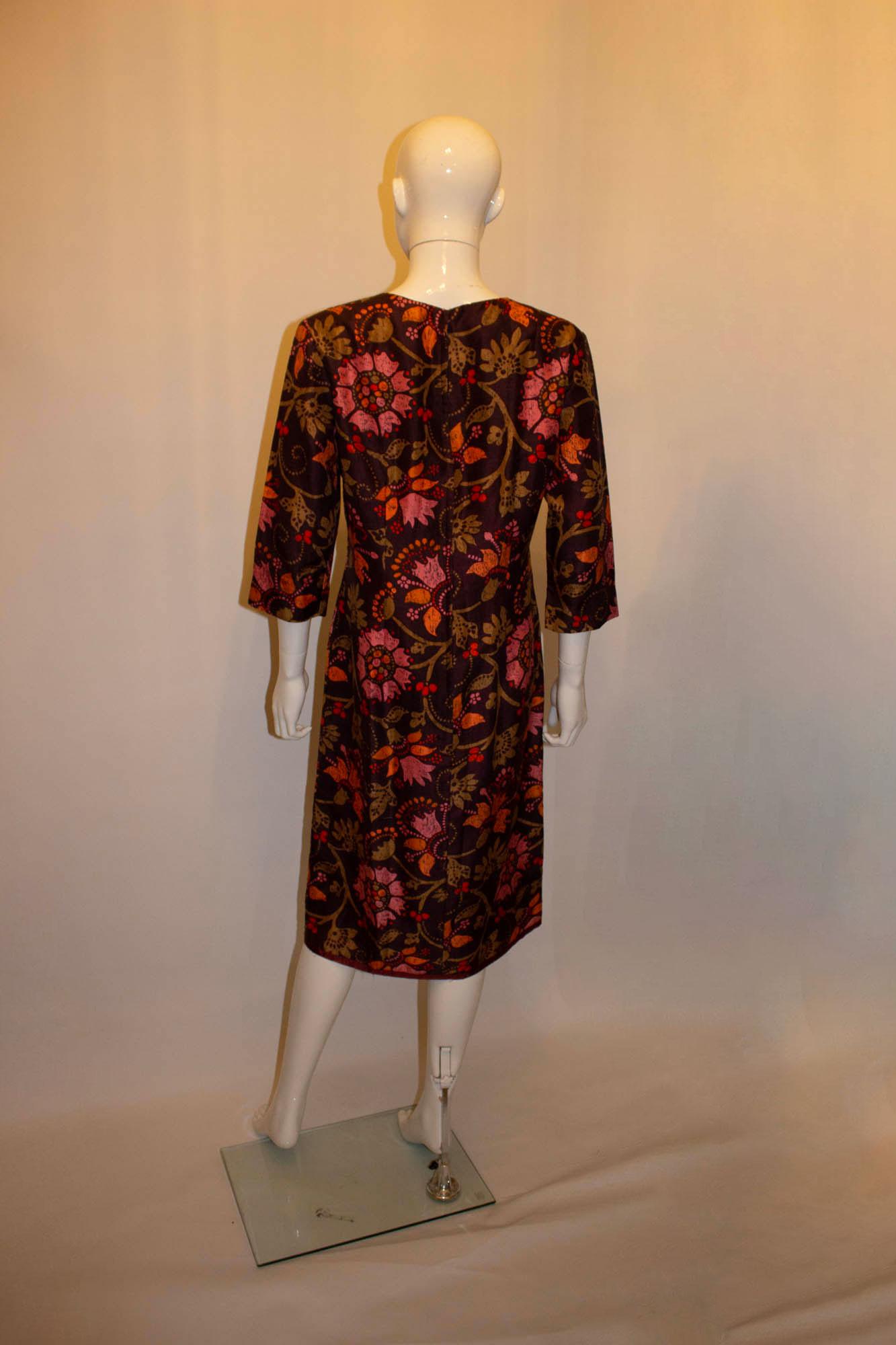 Une magnifique robe en soie de Bermard Frères ( Paris, Londres)  dans un imprimé Liberty. La robe a un fond marron, avec un motif rose et orange. Il présente une encolure ronde, des manches aux coudes et est entièrement doublé. Mesures : Buste
