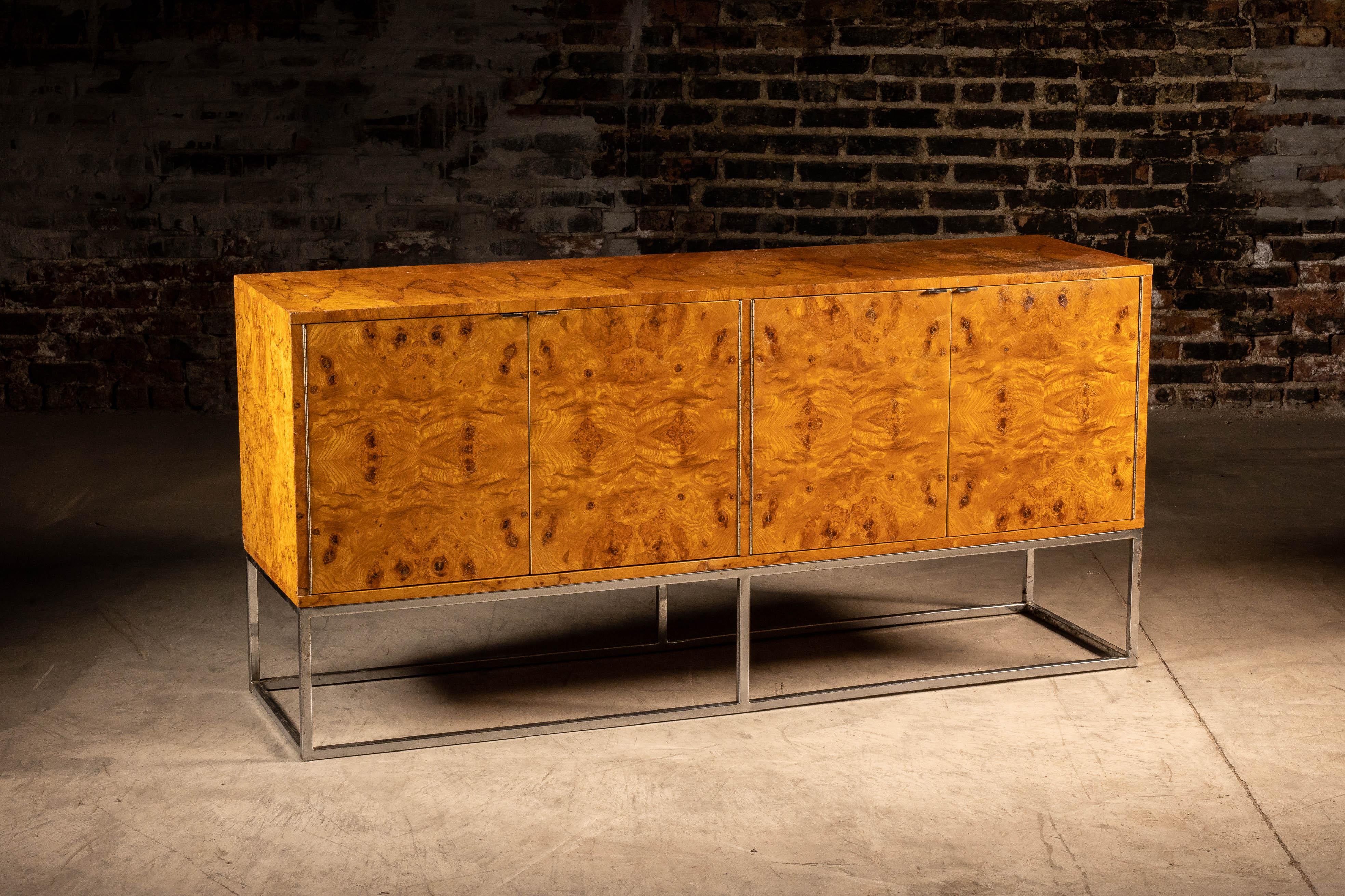 Cette crédence est fabriquée en placage de bois de ronce et comporte des pieds en métal à barre plate. Cette crédence a été fabriquée par Bernhardt et fait partie de la collection Flair, probablement dans les années 1970. Les portes de l'armoire de