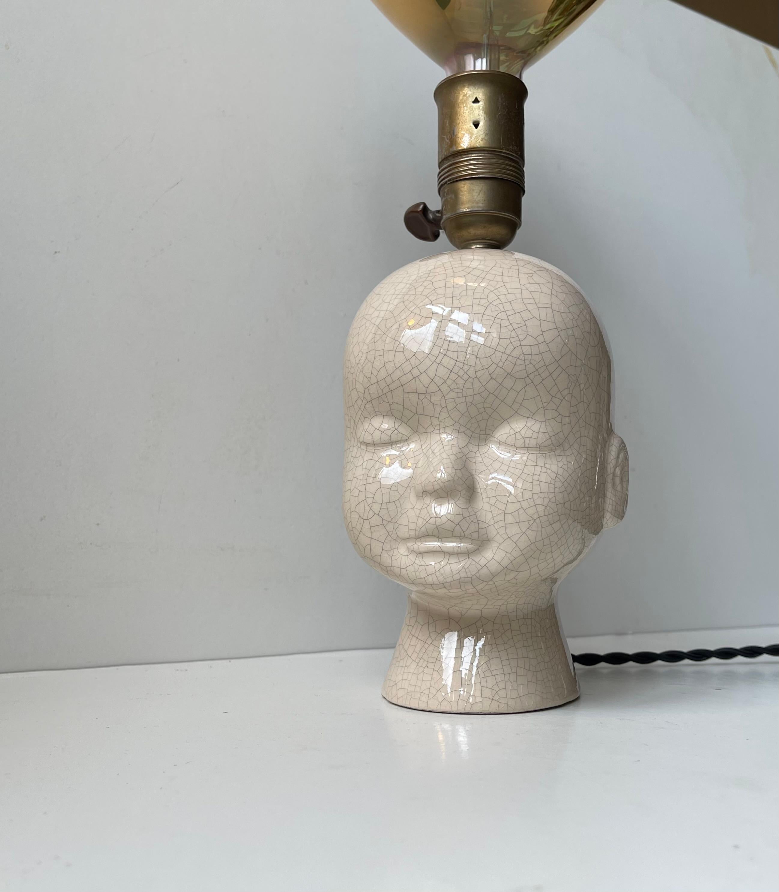 Unusual bespoke Table Lamp composed of a porcelain baby bust/head with faux craquele glaze and a decorative brass socket supporting the star of the show: A Golden balloon shaped jumbo bulb that mirrors its surroundings. This type of bulb were made