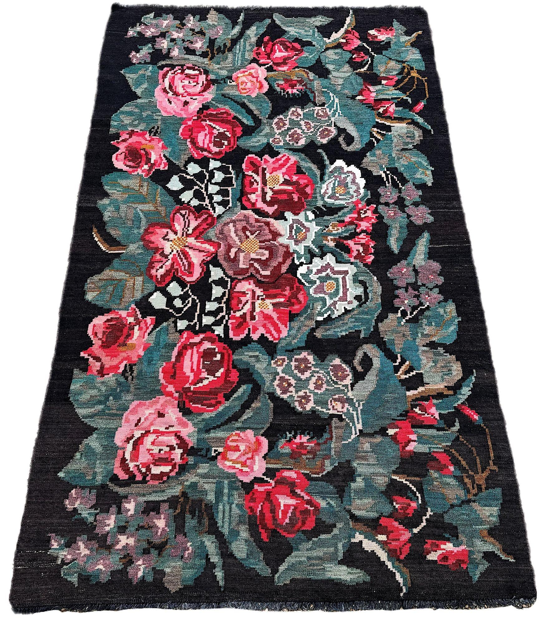 Un bellissimo kilim bessarabiano d'epoca, probabilmente tessuto in Moldavia nella seconda metà del XX secolo. Questo kilim presenta un disegno allover di fiori e foglie interconnessi su un campo di carbone. Bellissimi colori secondari di rosso, rosa
