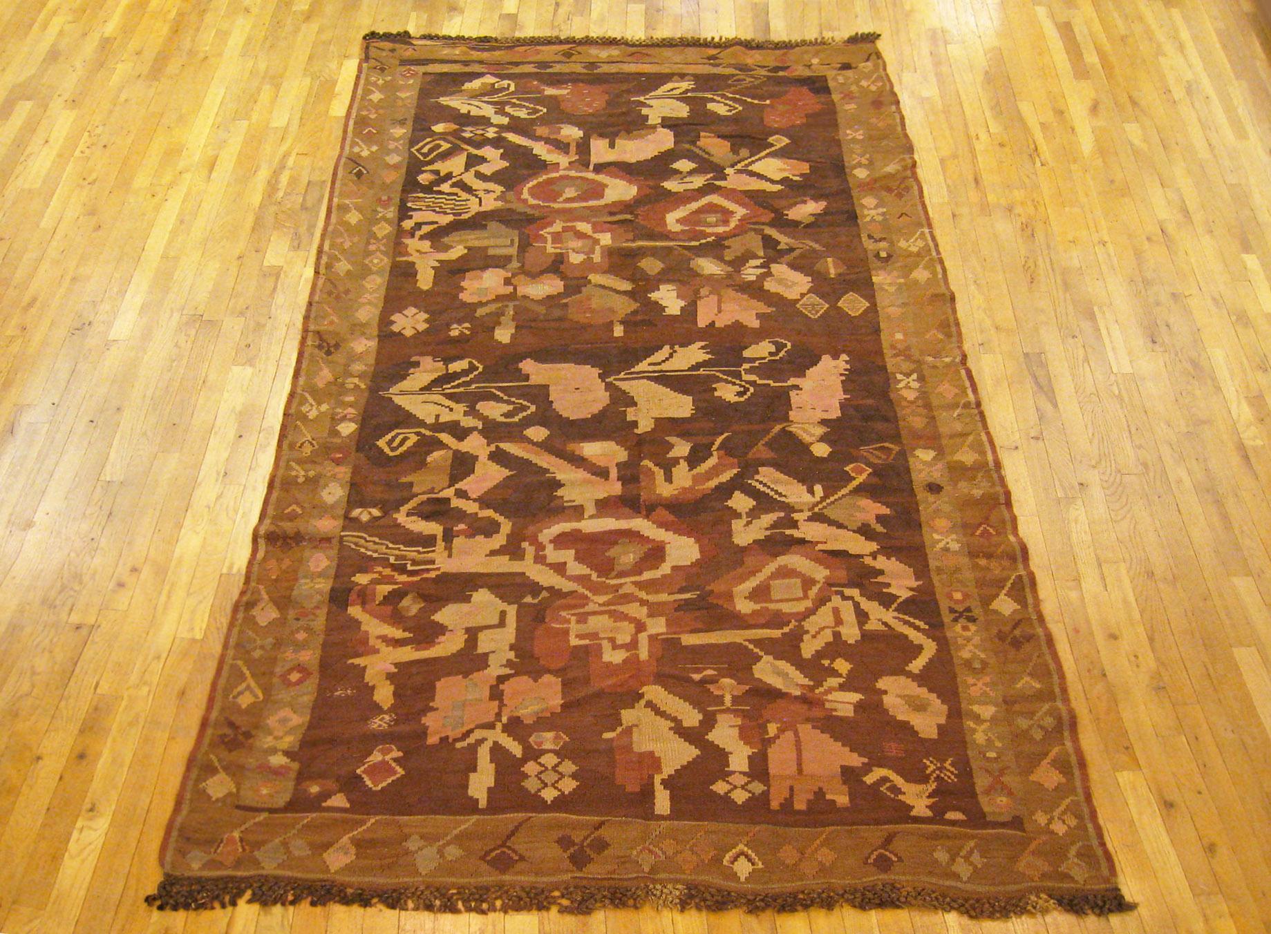 A vintage Bessarabian Kilim oriental rug in kaleghi (gallery) size, size 11'0 x 5'6, circa 1930. This handsome handmade flat-woven carpet has no upward pile, and features a stylized large scale floral design in the brown central field. The field is