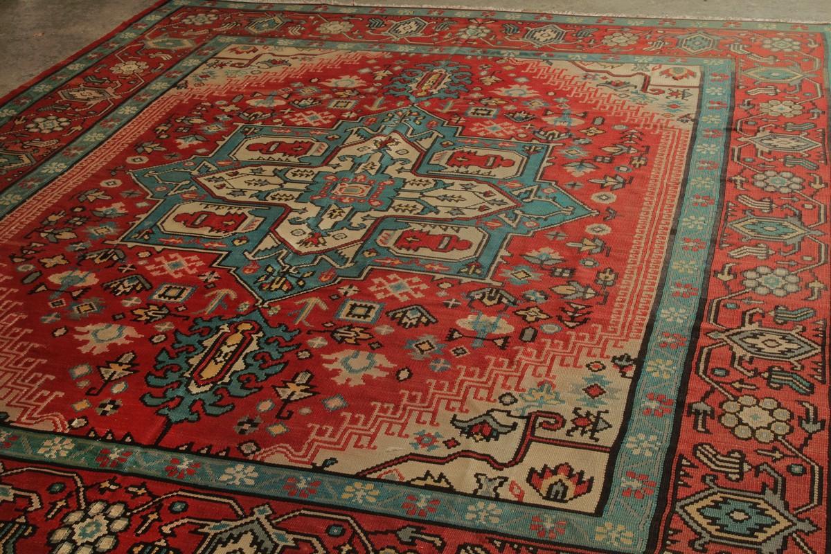 Dieser seltene 9x10 große Kelim, der um 1950-1960 in Wolle handgewebt wurde, stammt vermutlich aus Bessarabien. 

Über das Design: Ebenso ungewöhnlich wie der Maßstab ist das Design, denn nur wenige Flachgewebe dieser Art sind mit dieser