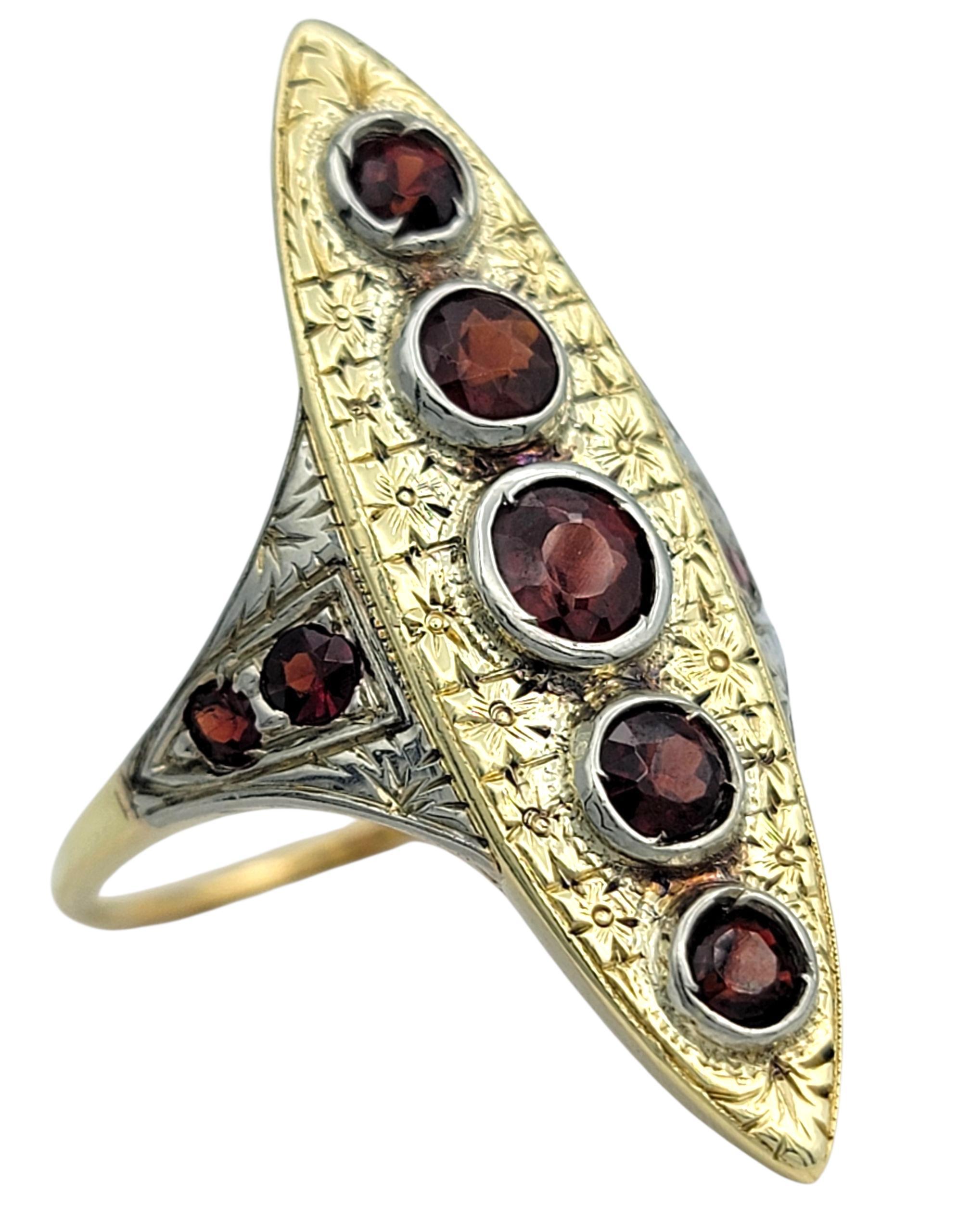 Dieser Ring im Vintage-Stil zeigt eine markante marquiseförmige Silhouette, die mit tiefroten Granaten besetzt ist, die warm auf dem Gold leuchten. Jeder Granat ist in einer vertikalen Linie angeordnet, eingerahmt von einem fein strukturierten Rand,