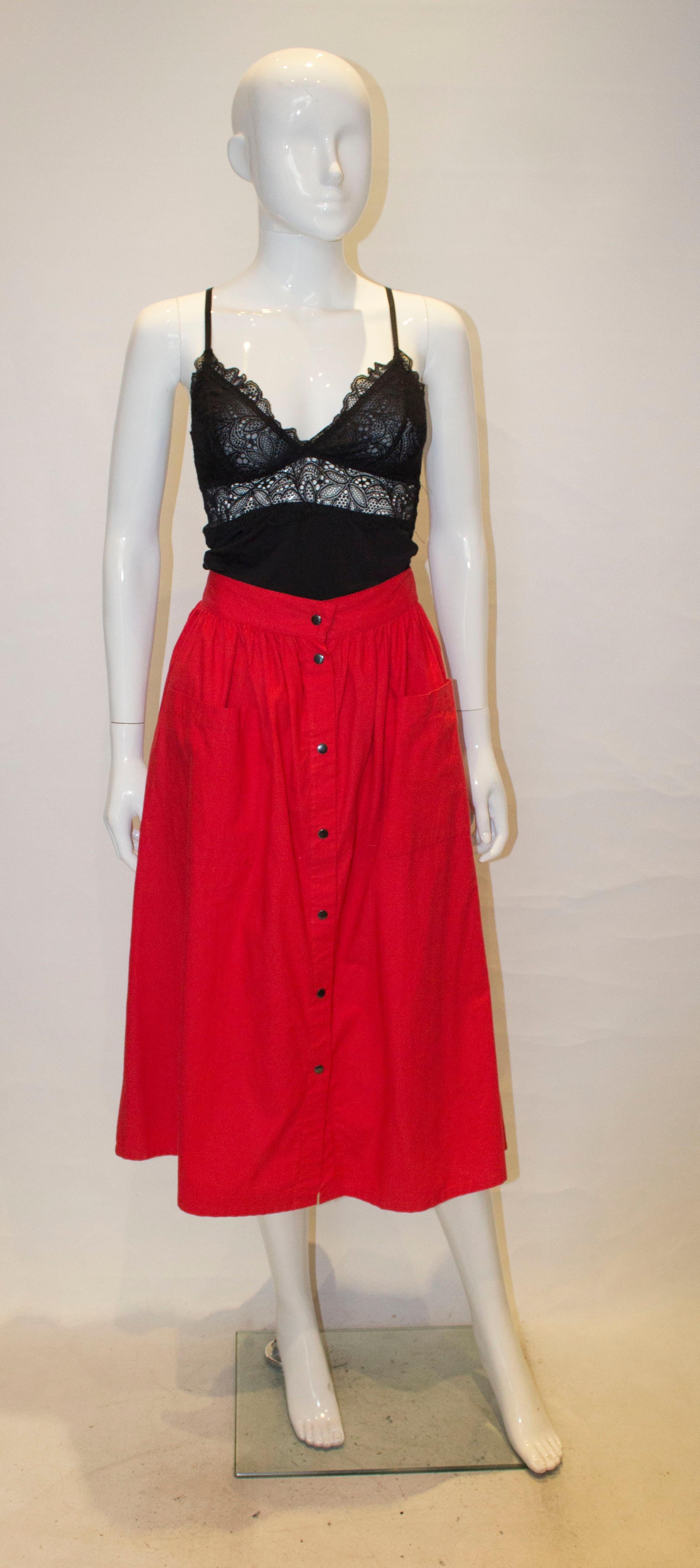 A fun vintage skirt by Biba. In a red cotton the skirt has gathering at the waist, a front popper opening and two pockets on the front. It is unlined.