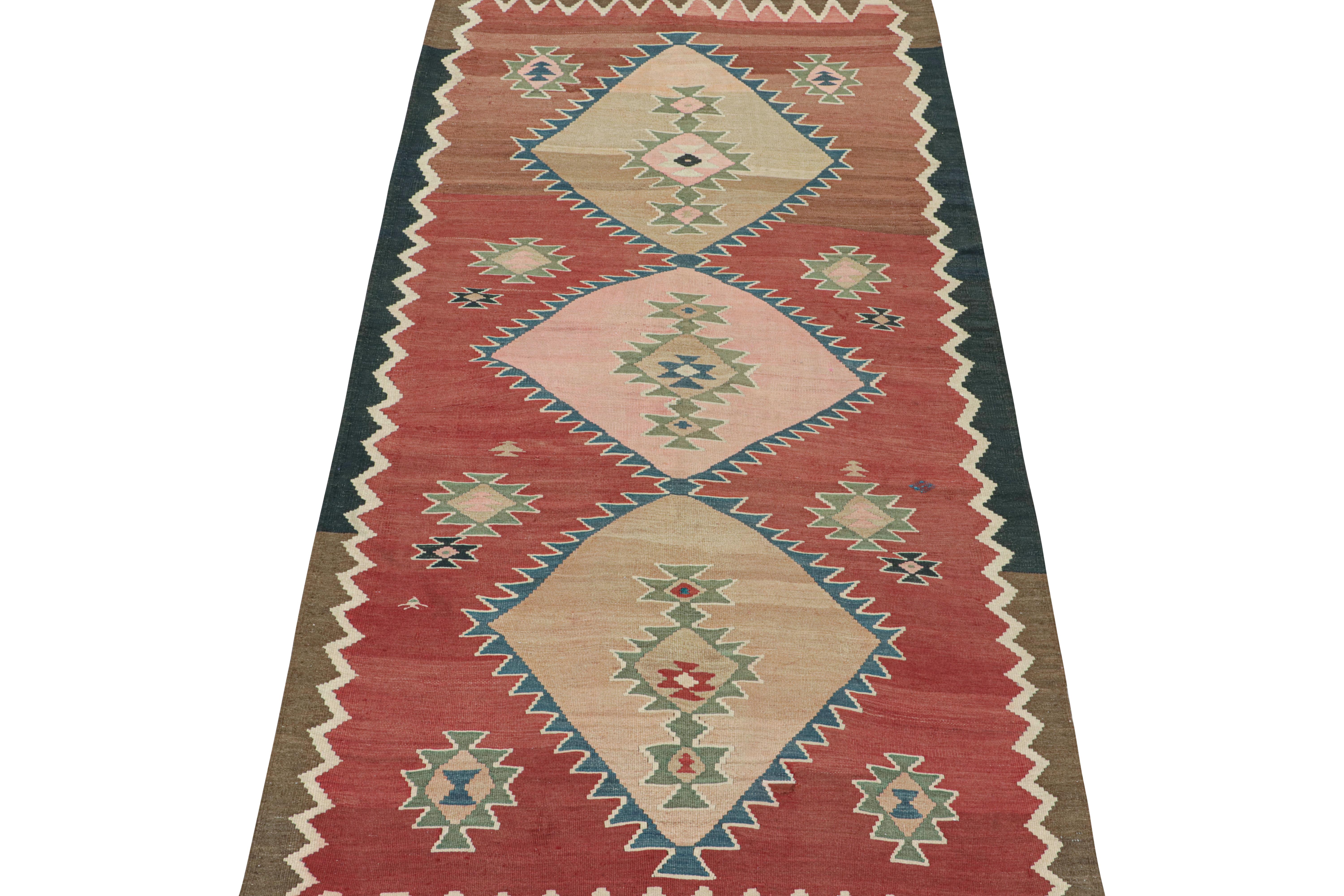 This vintage 6x11 Persian Kilim is believed to be a Bidjar tribal rug of the 1950s. Handwoven in wool.

Its design includes three large diamond-shaped medallions in beige and pink on a brick red field. Keen eyes will further admire off-white,