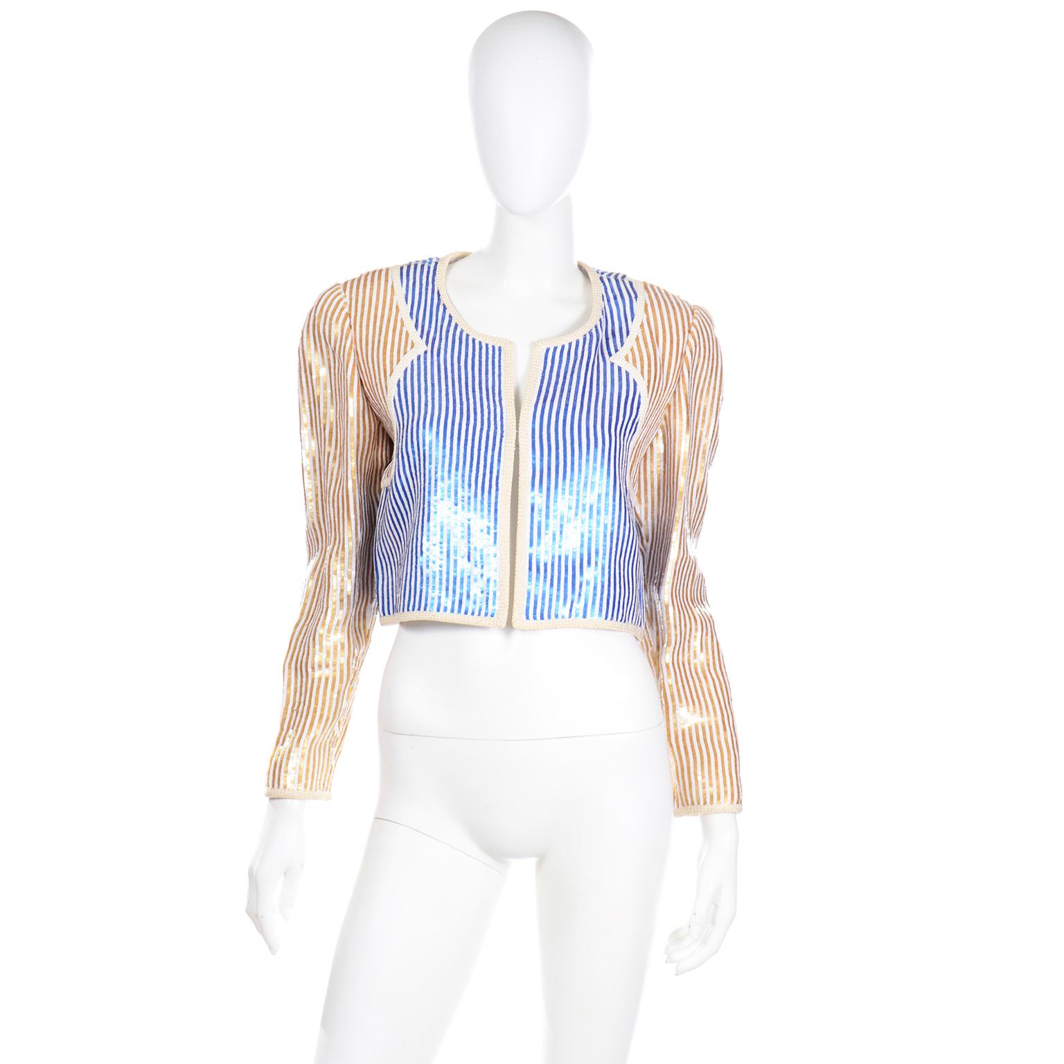 This gorgeous vintage Bill Blass evening jacket is completely covered in mini blue, white and gold paillettes. The jacket has ivory braided trim and is open in the front. This would be a perfect piece to wear with high waisted pants, a skirt or over