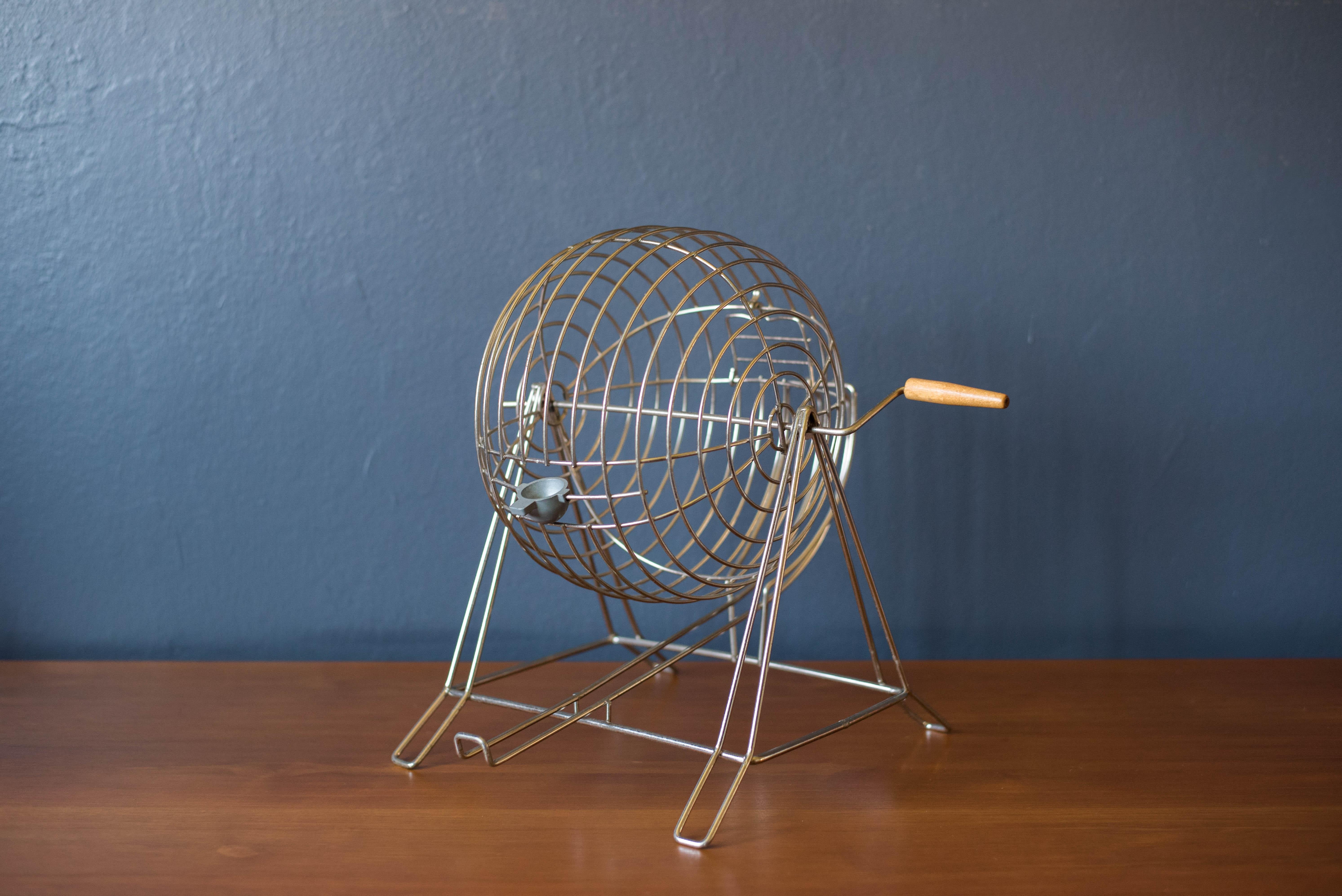 Vintage original Bingo game set, circa 1950s. This set includes the metal cage with rotating wood handle, wooden token red embossed markers, and wooden numbered balls stamped in blue. Great accessory for a game room. The set does not include bingo