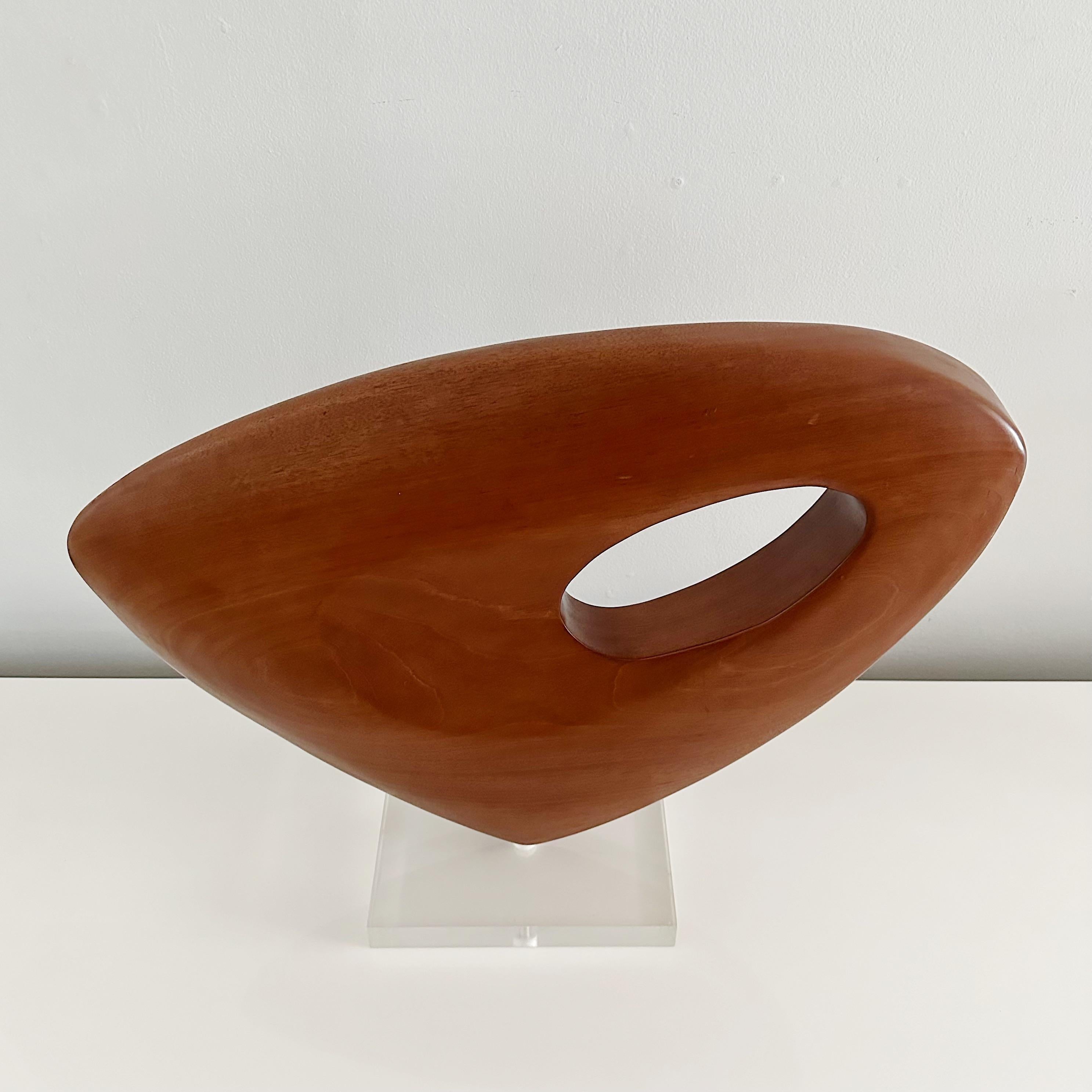 .

This biomorphic organic sculpture is hand carved from one large piece of walnut wood. Showcasing an interesting exploration of negative space, the piece features an oval cutout near the top corner. This stately yet modern design is mounted on a