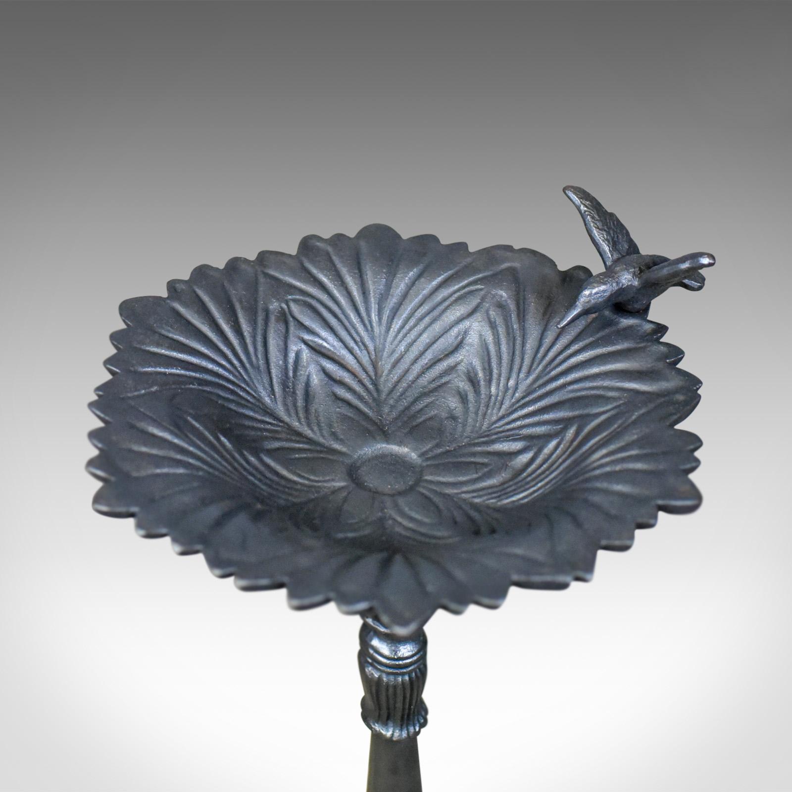 This is a vintage birdbath. A cast-iron feeder or planter dating to the late 20th century.

Consistent colour throughout
Bird sculpture decorates the bath perimeter
Decorative floral design with copious petal detail
Supported by a turned,